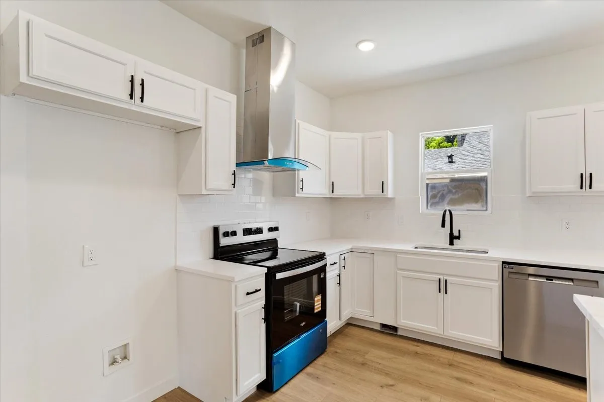 White shaker cabinetry, stainless steel appliances, a tile backsplash, white countertops, and wood-finish flooring