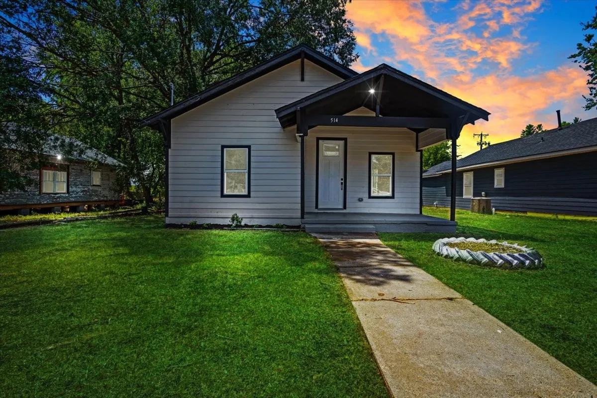 White exterior siding with dark trim, covered front porch, and a concrete pathway