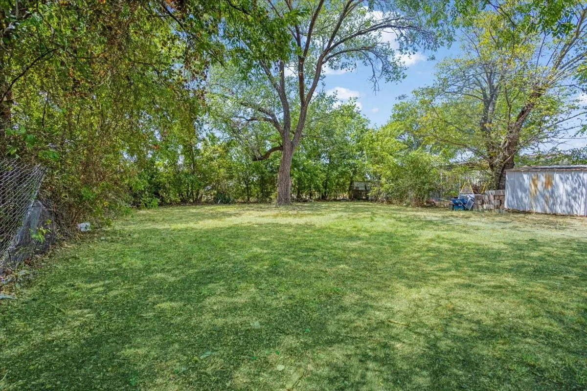 Expansive lawn with mature trees and perimeter fencing