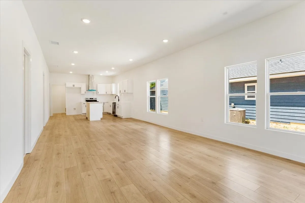 Open-concept living area featuring wood-finish flooring, recessed lighting, and multiple windows