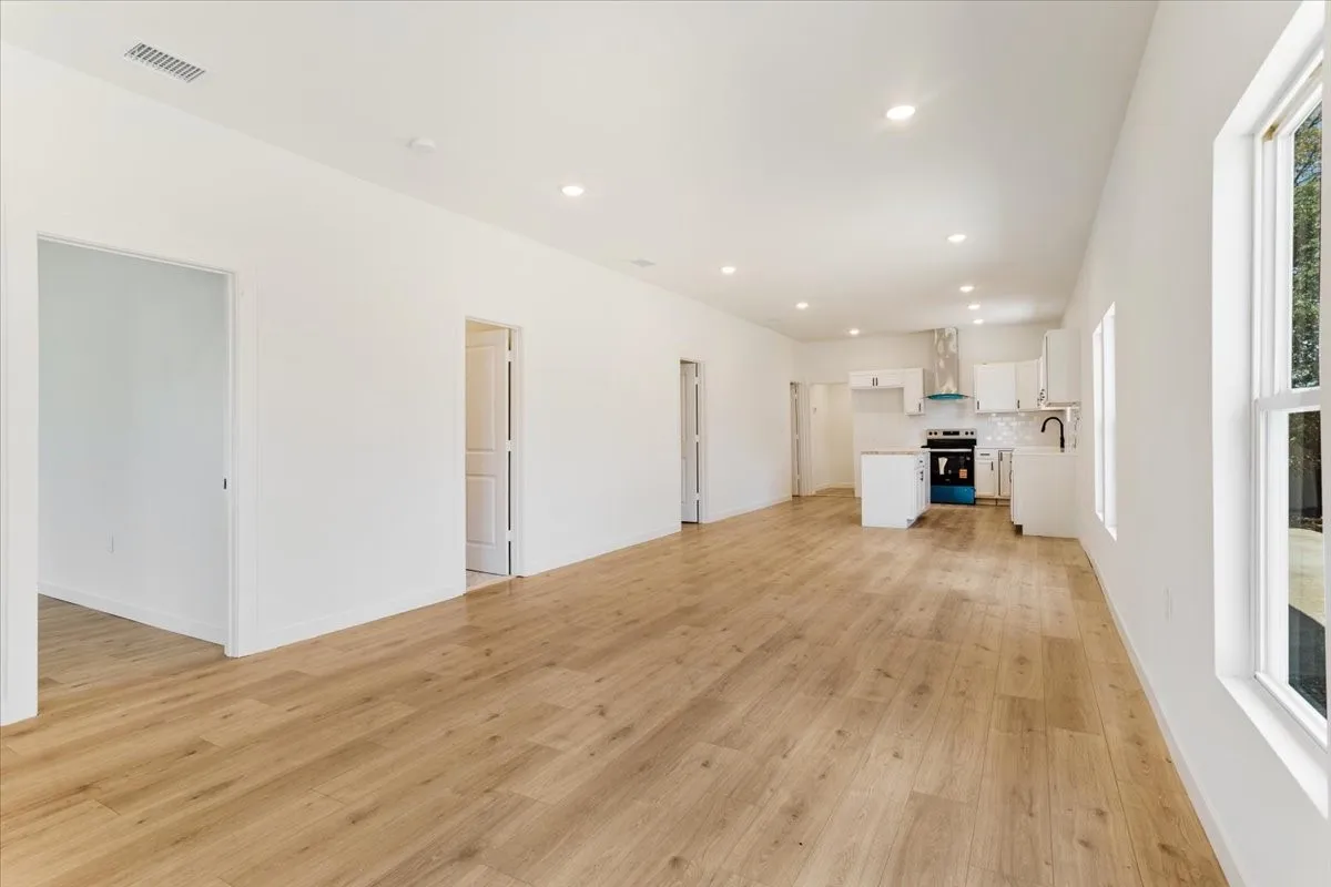 Open concept living space with wood-finish flooring, white walls, and recessed lighting