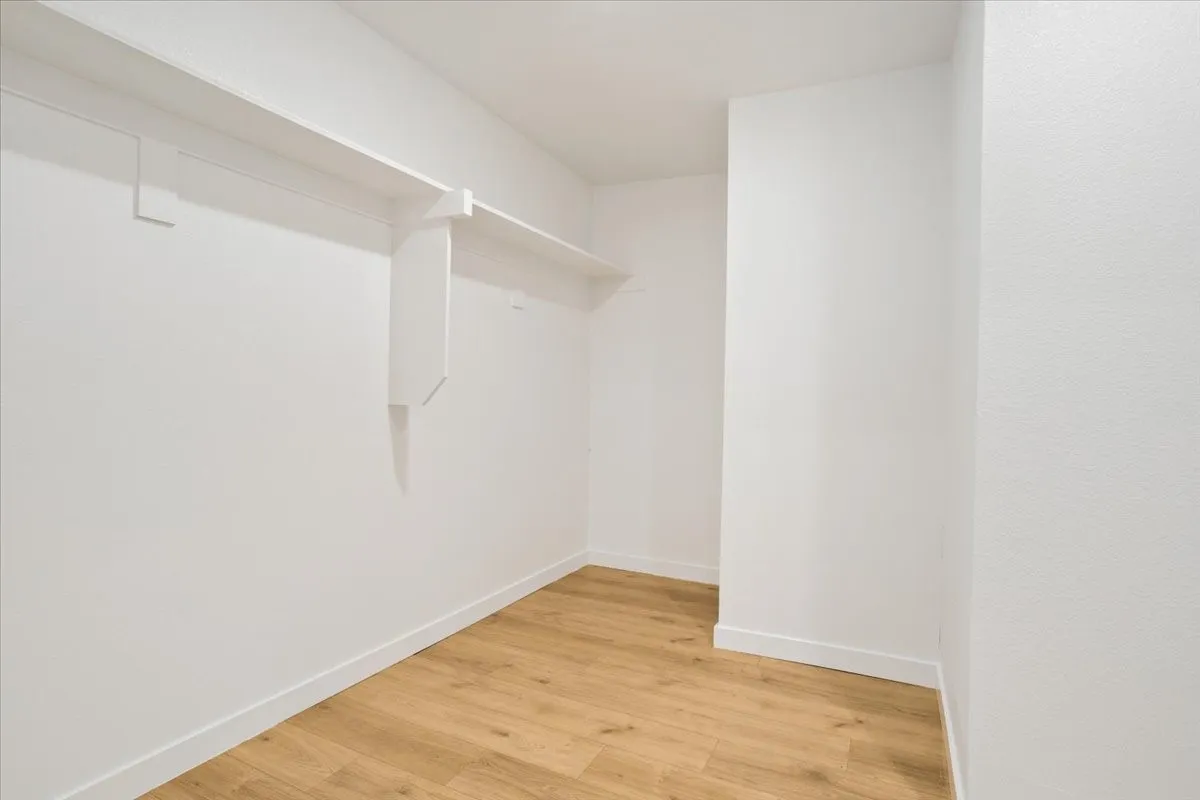 Built-in shelving with hanging rod, wood-finish flooring, and crisp white walls
