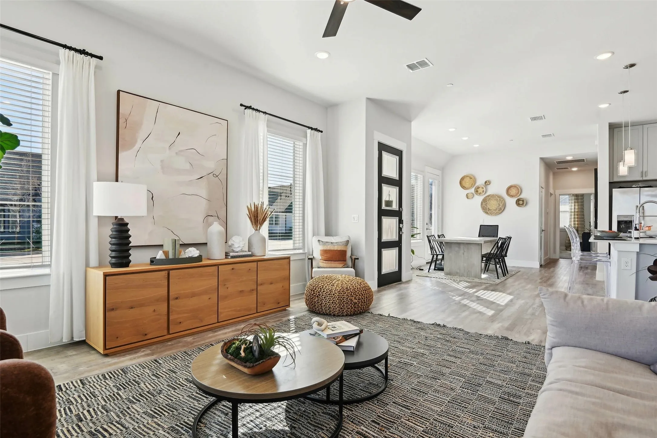 Open-concept living area featuring wood-finish flooring, recessed lighting, and large windows with blinds