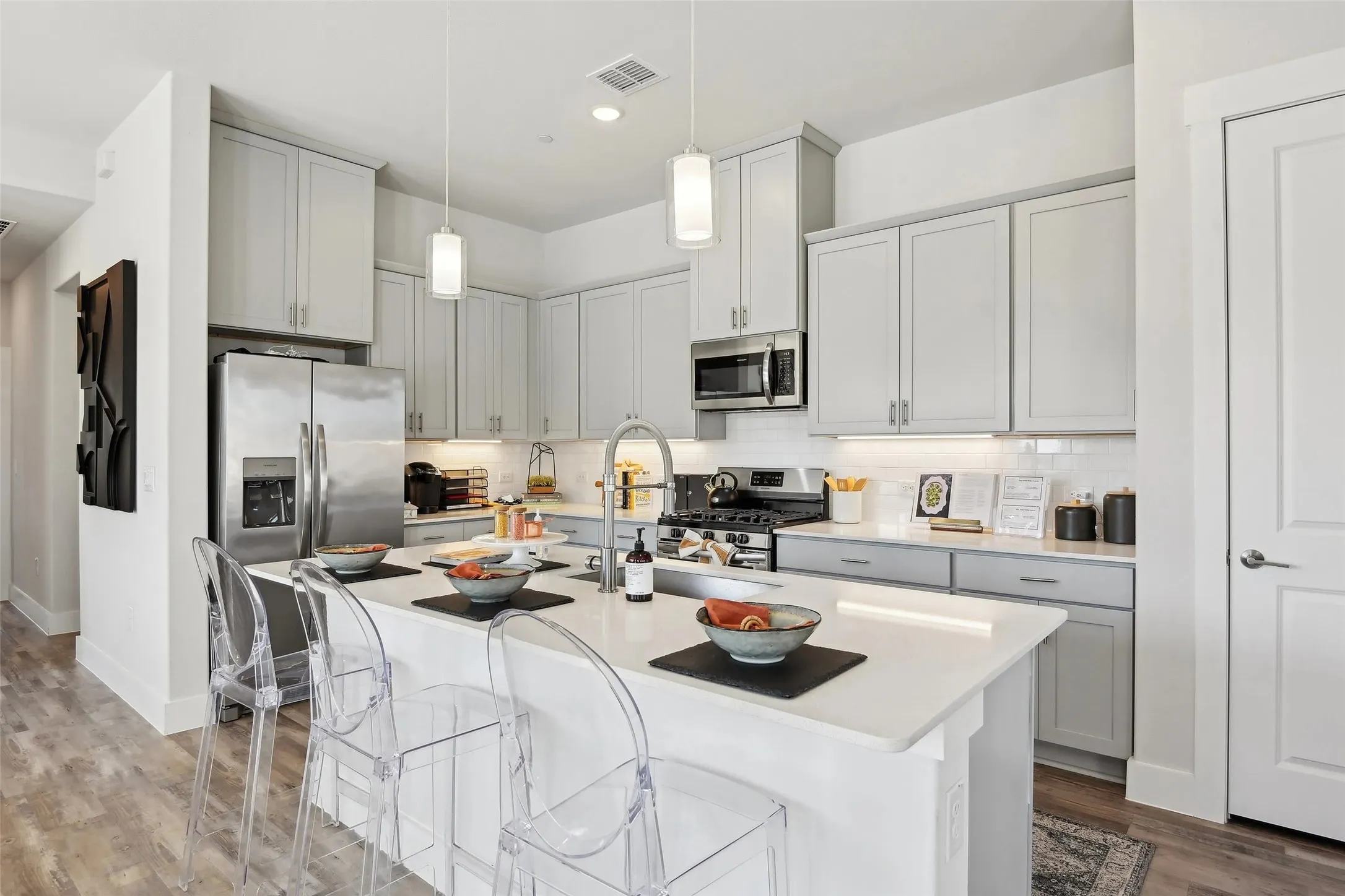 Kitchen featuring a center island with countertop seating, stainless steel appliances, light gray cabinetry, and wood-finish flooring