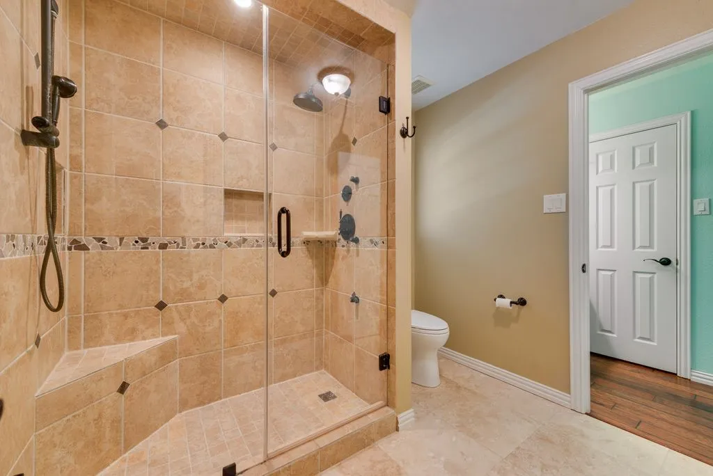 Large shower with toilet, privacy doors separate the Jack and Jill: large vanity area, 2 on one side, and 1 vanity one the other.