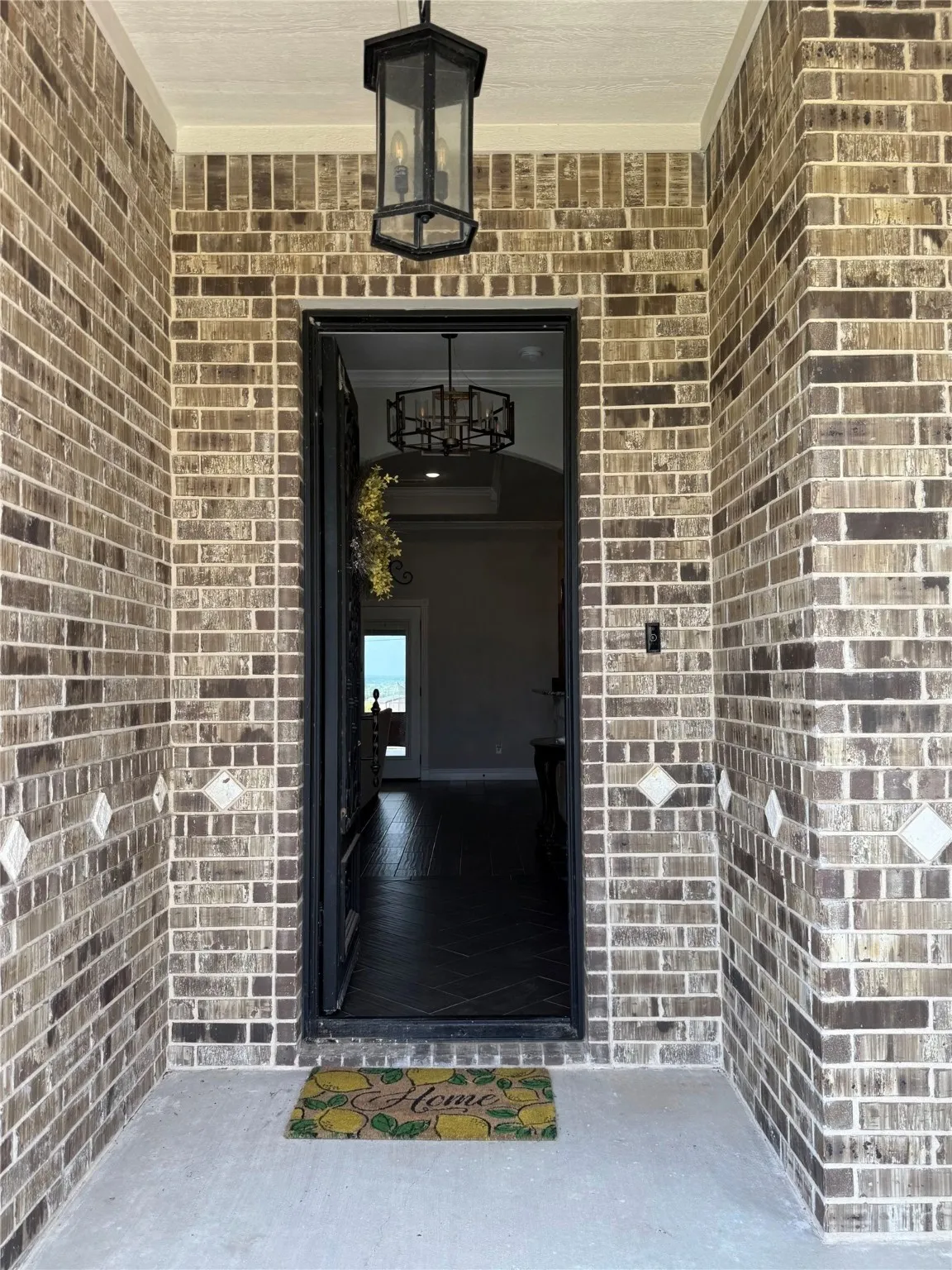 Brick exterior with decorative tile accents, a black wrought iron entry door, and an exterior lantern fixture