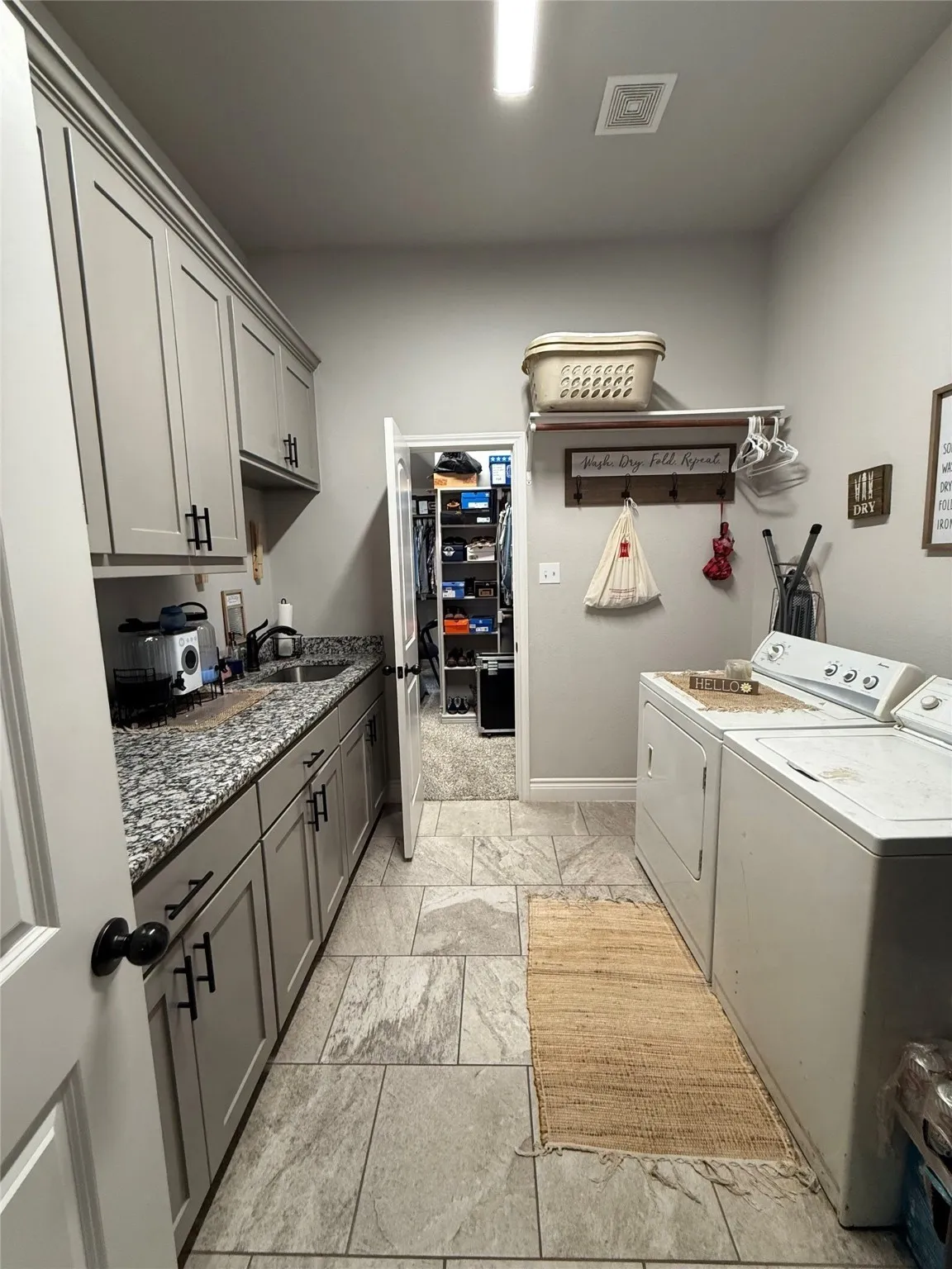 Utility room featuring extensive built-in cabinetry, durable countertops, and large format floor tiling