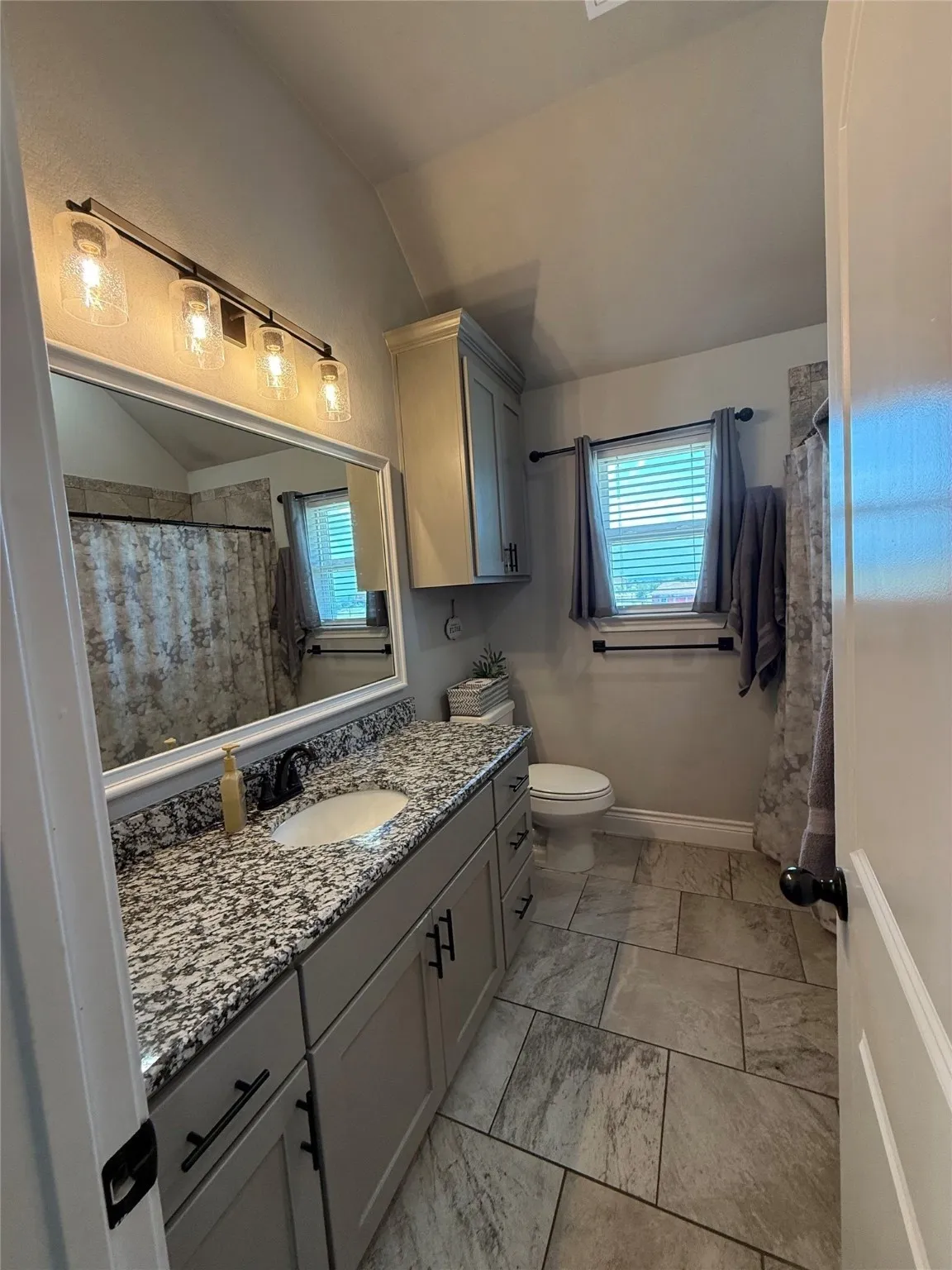 Vanity with granite countertop, integrated sink, and gray cabinetry