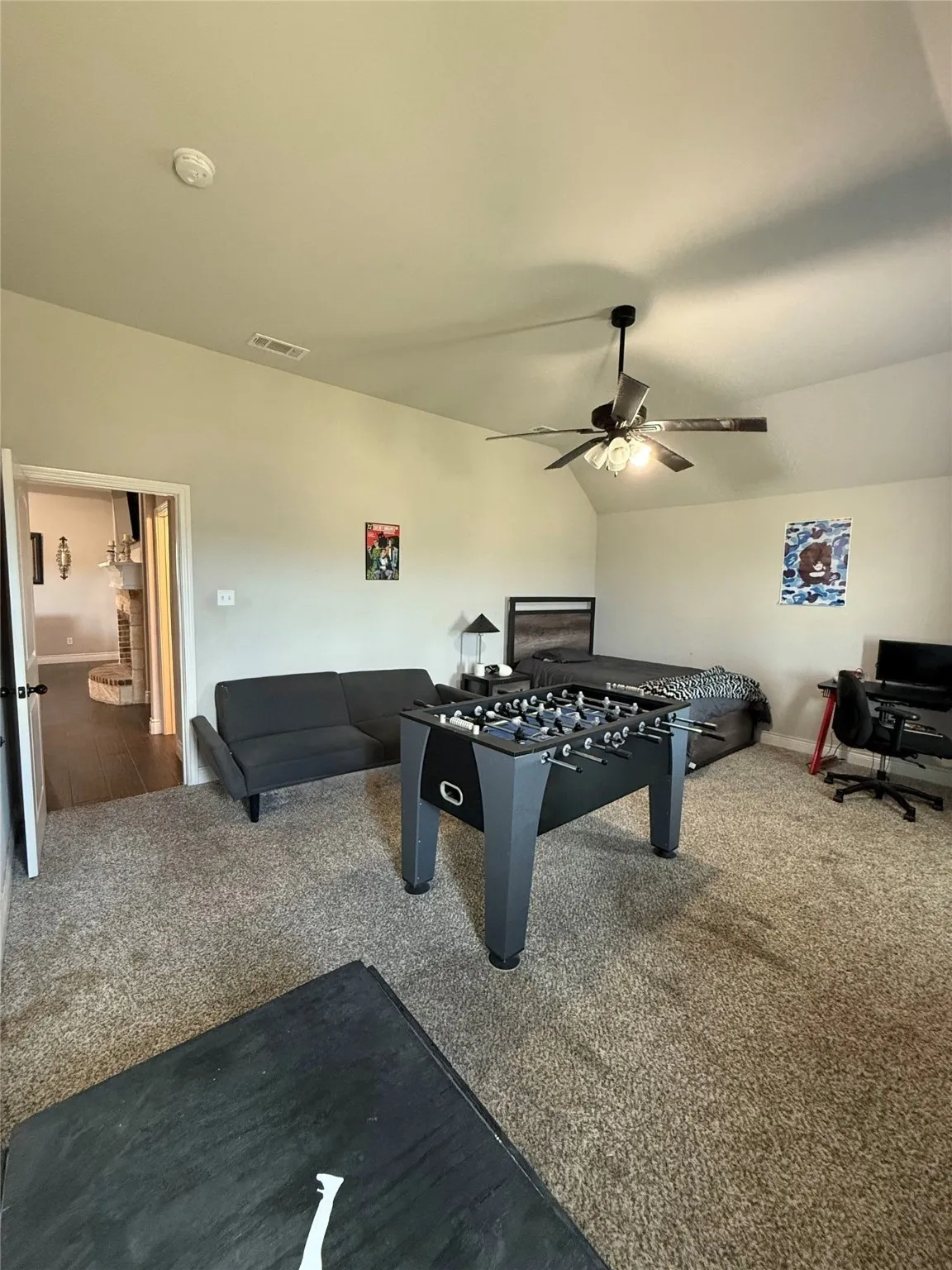 Carpeted room with vaulted ceiling and a ceiling fan