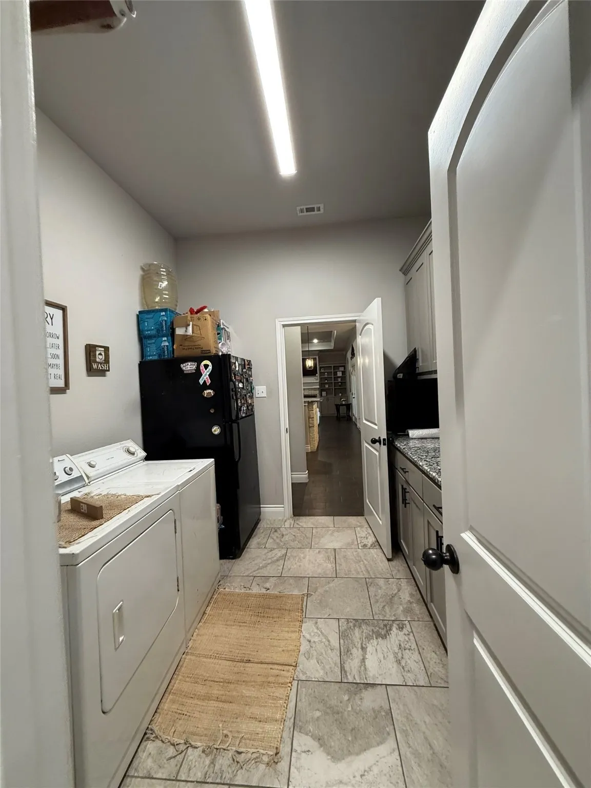Gray tile flooring, light gray cabinetry, and a dark countertop