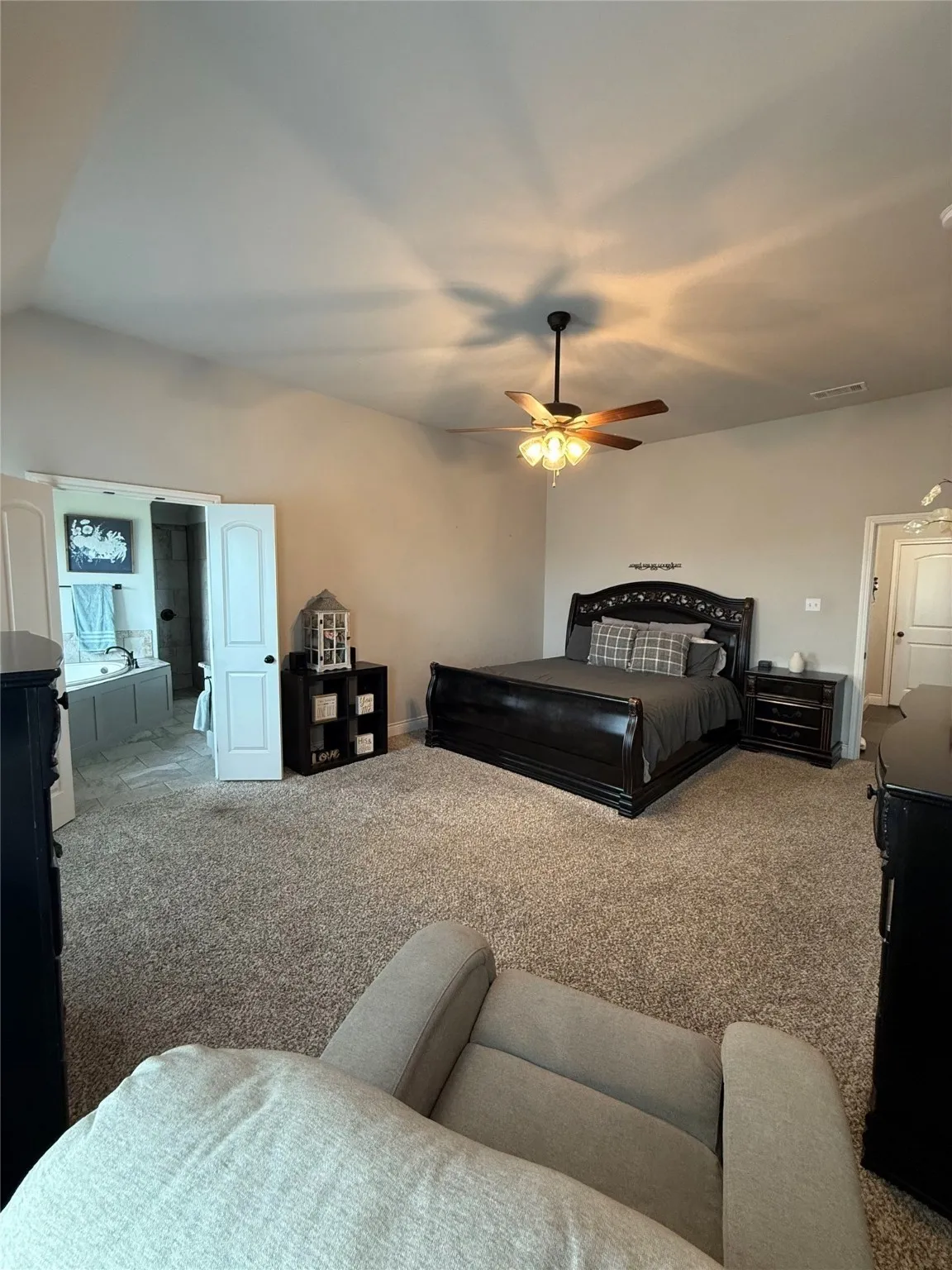 Carpeted flooring throughout the room, ceiling fan with integrated lighting, and a white paneled door