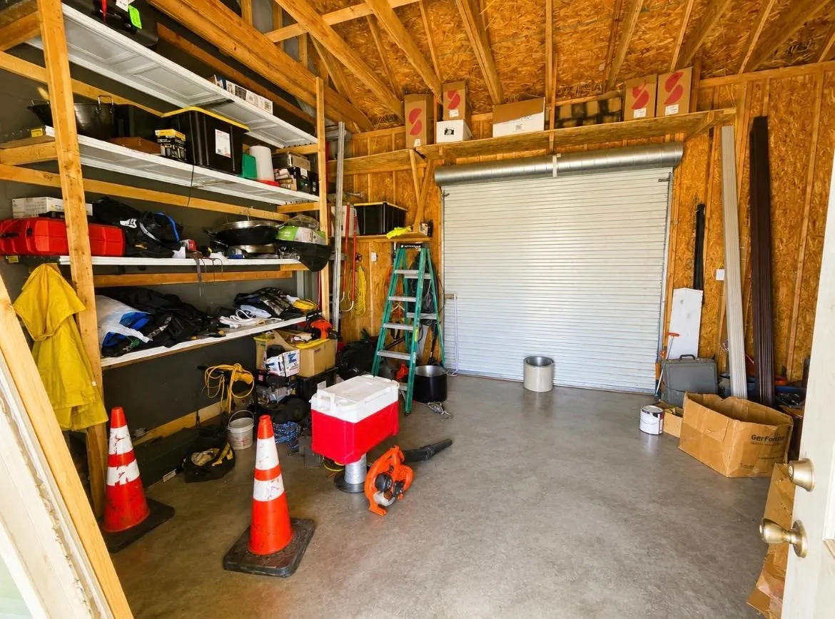 Enclosed garage space featuring a roll-up door, exposed ceiling joists, and a concrete floor