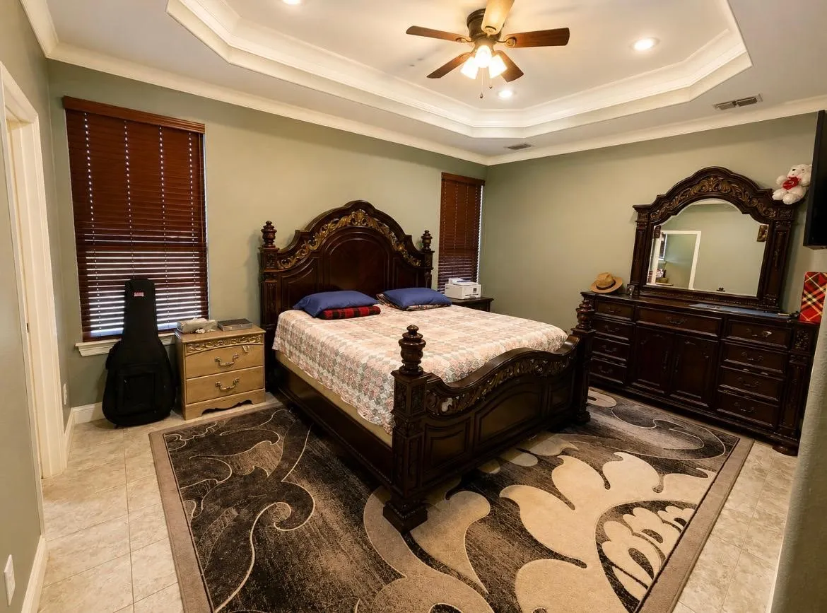 Tray ceiling with recessed lighting and a ceiling fan, tiled flooring, and window treatments
