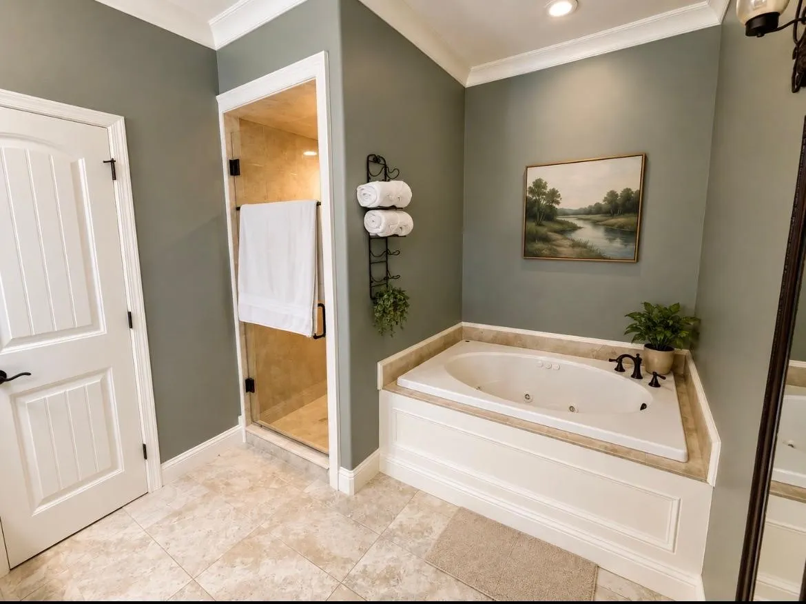 Built-in soaking tub with a stone surround, glass-enclosed shower, paneled door, crown molding, and tile flooring