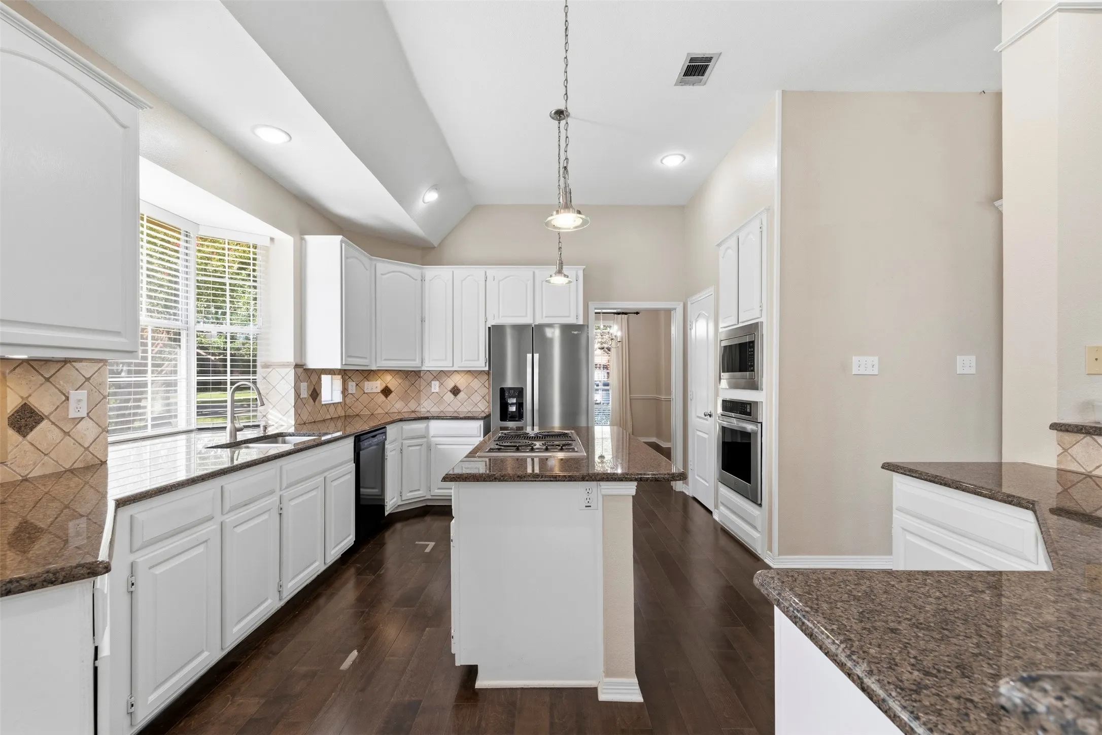 Kitchen featuring white cabinetry, dark wood-finish flooring, granite countertops, and stainless steel built-in appliances