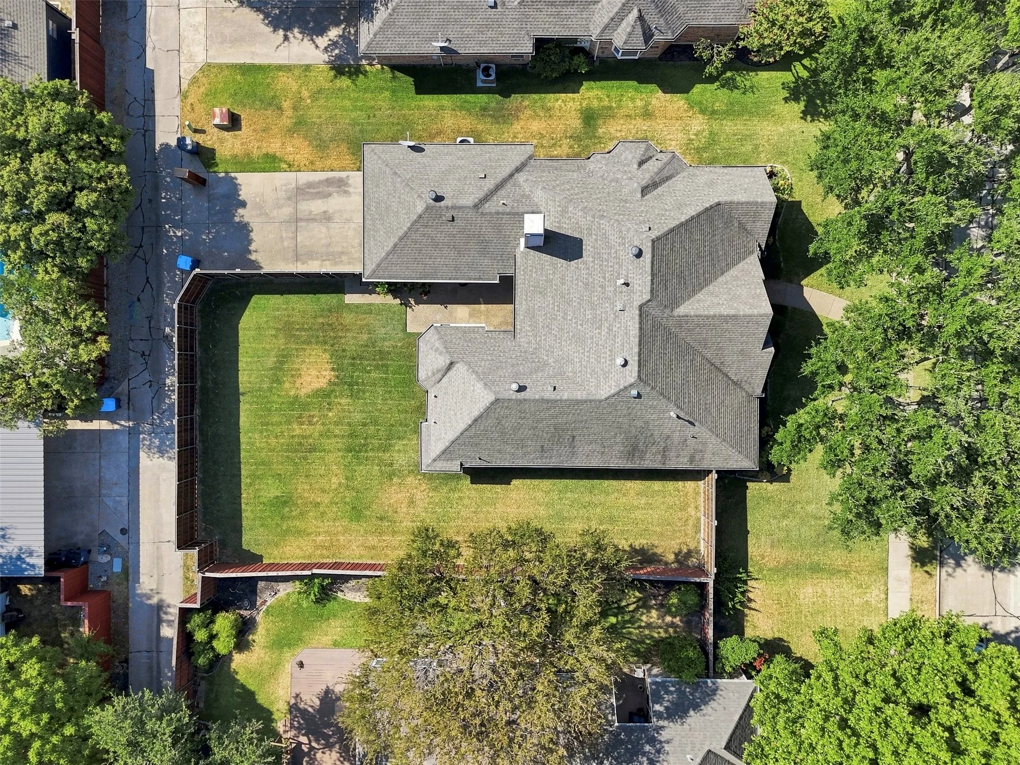 Expansive property featuring a gabled roofline, substantial backyard, concrete driveway, and mature landscaping