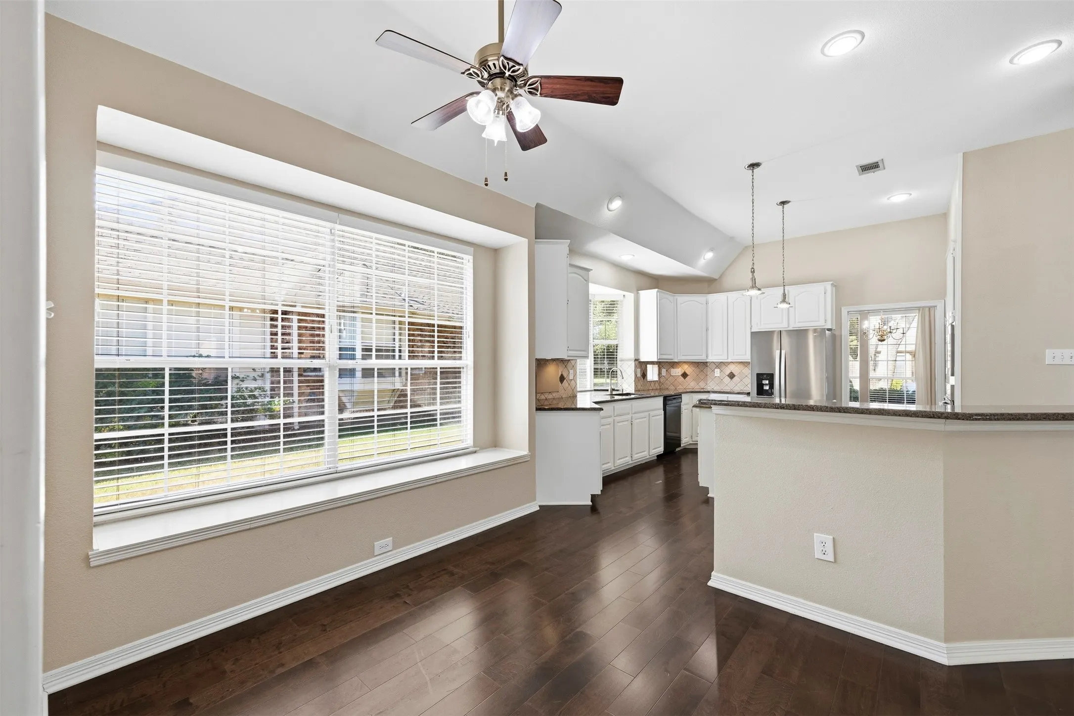 Vaulted ceilings, recessed lighting, and a ceiling fan enhance the open-concept design