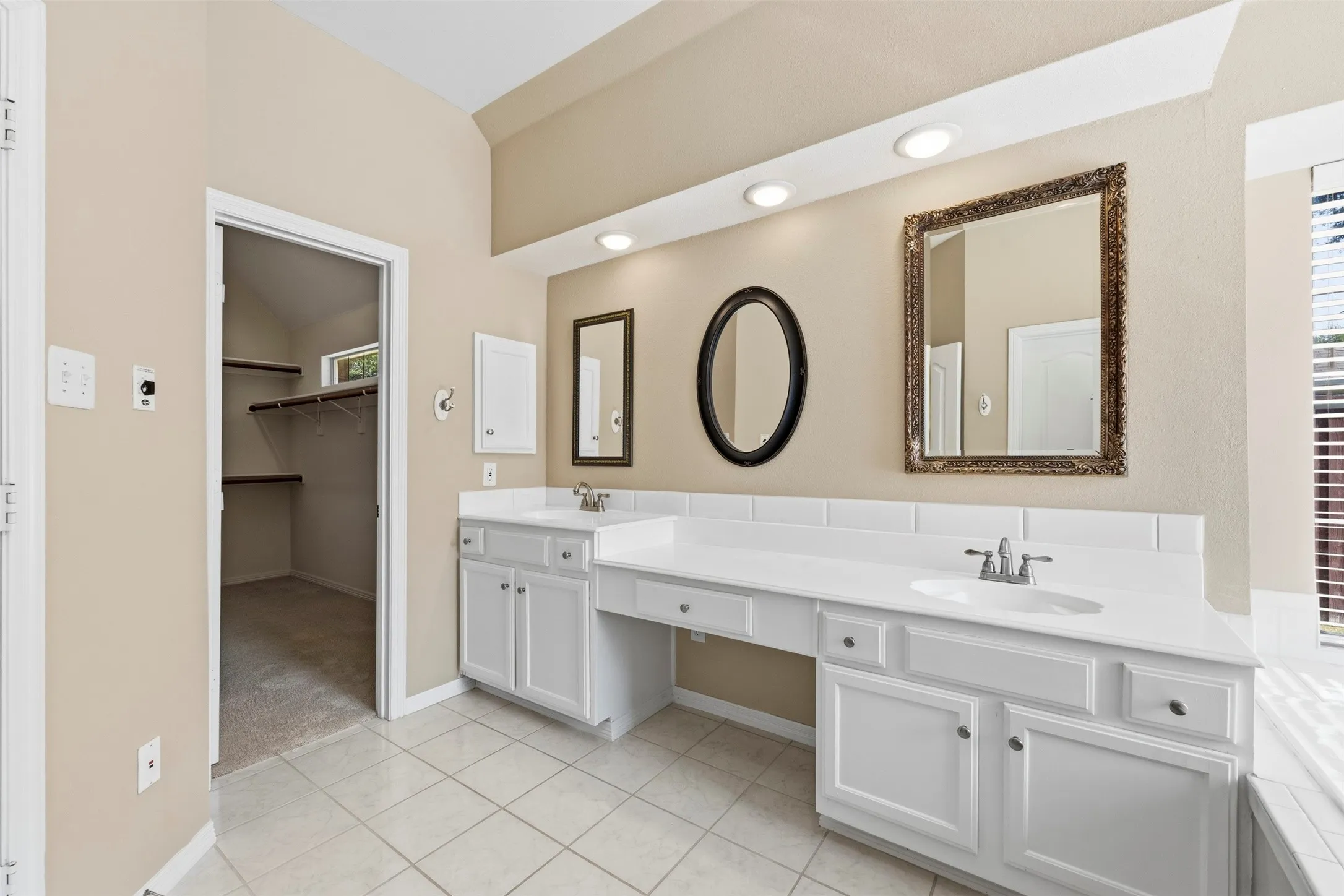 Dual sink vanity with white cabinetry, recessed lighting, and tiled flooring