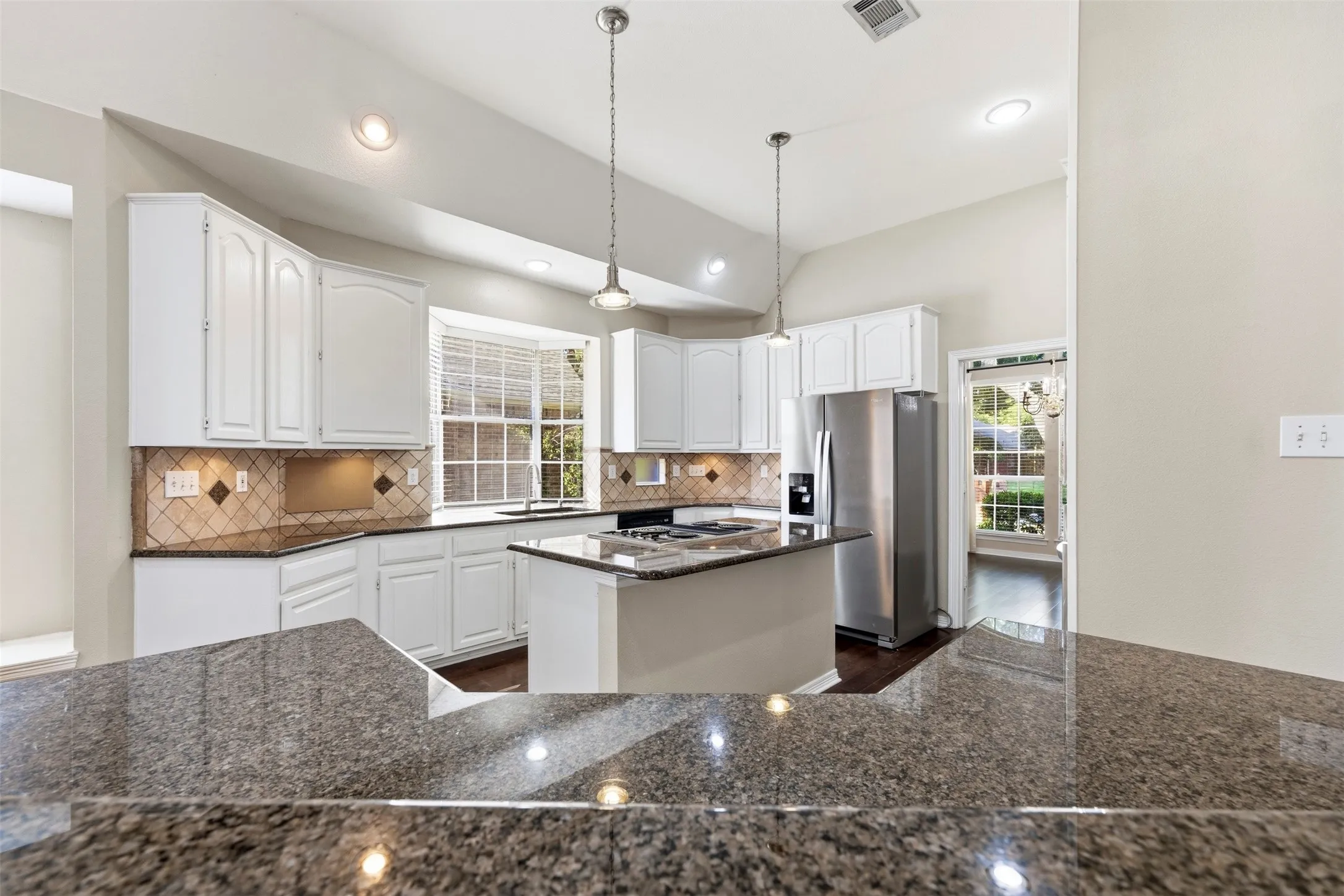 Kitchen featuring white cabinetry, granite countertops, tile backsplash, and stainless steel appliances