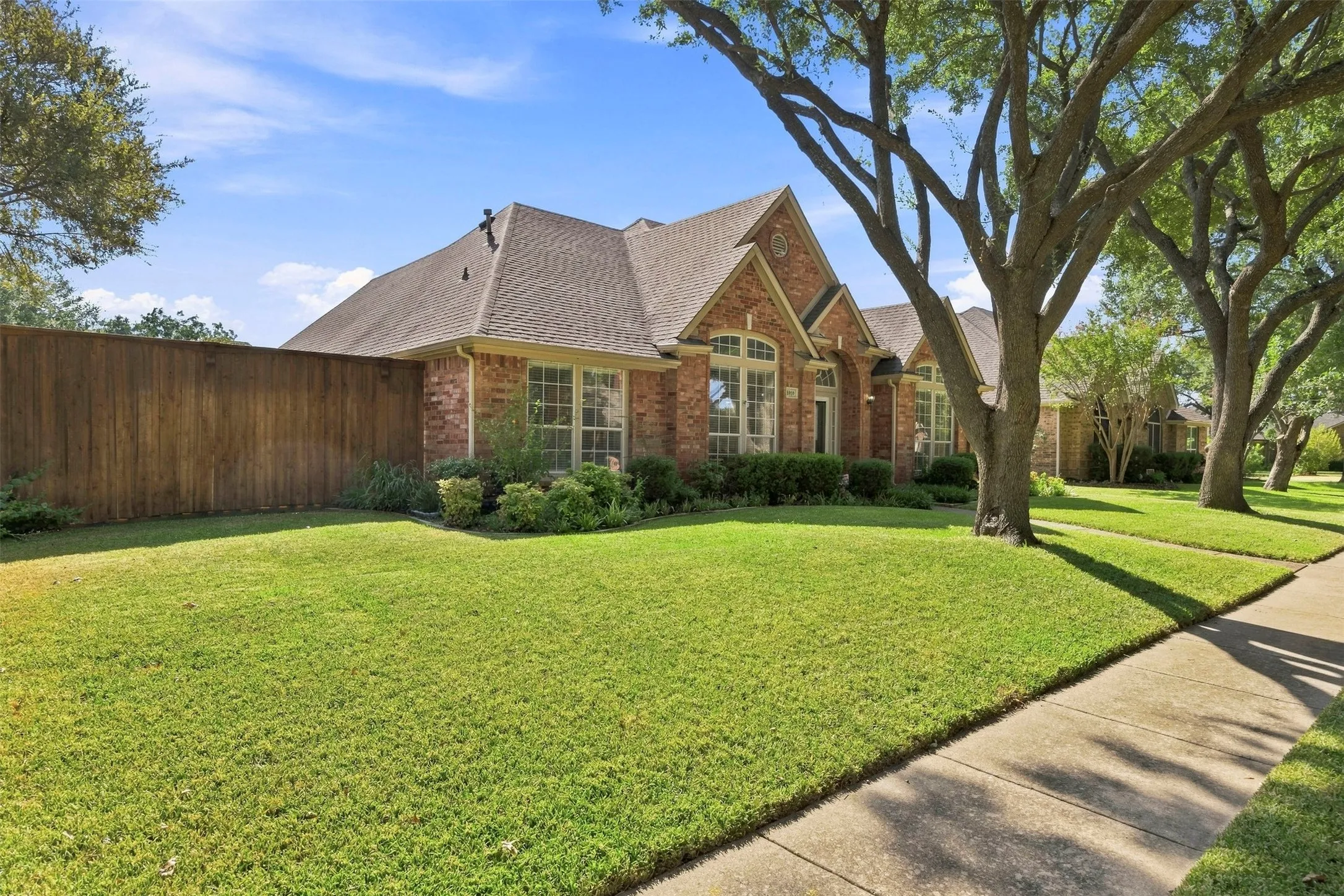 Brick exterior with a gabled roof and a wooden privacy fence