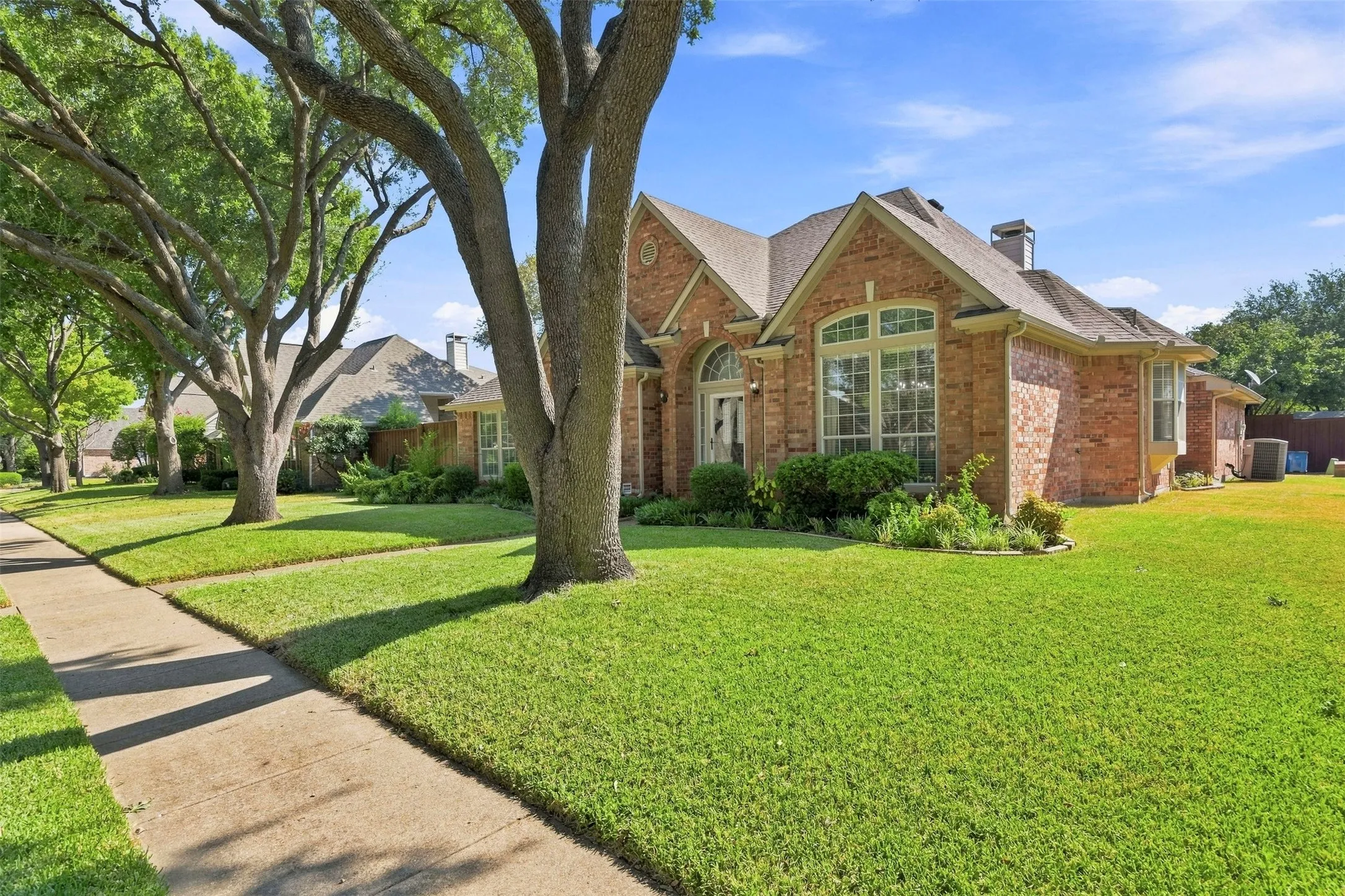 Brick exterior with multiple gables, arched entry, and bay window