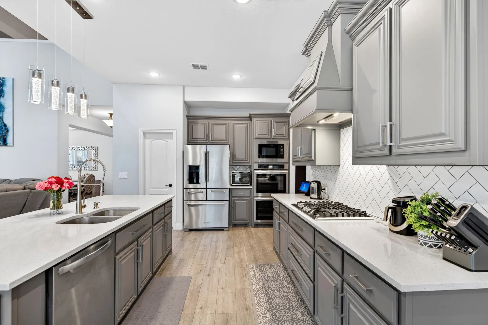 Beautiful quartz countertops, herringbone pattern ceramic backsplash, custom cabinets, gas cooktop vents to outside.