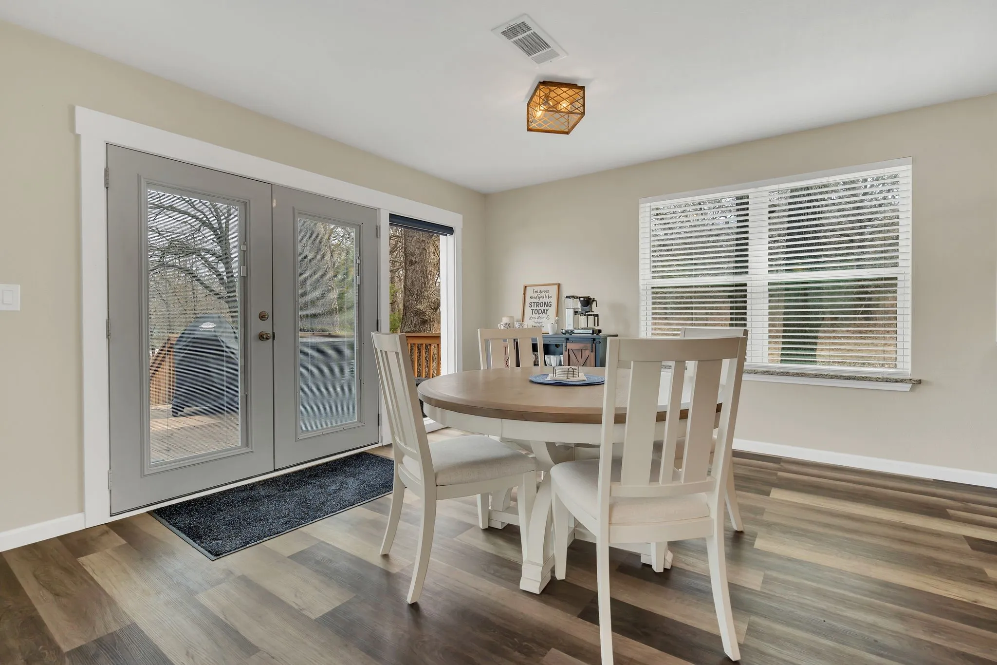 Wood-finish flooring, recessed ceiling lighting, a window with blinds, and double glass-paneled doors with a built-in transom