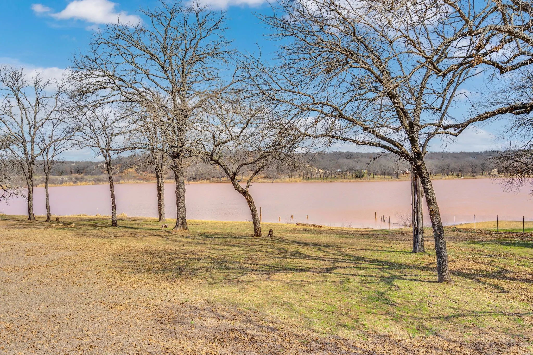 Expansive grassy area featuring mature trees and waterfront access