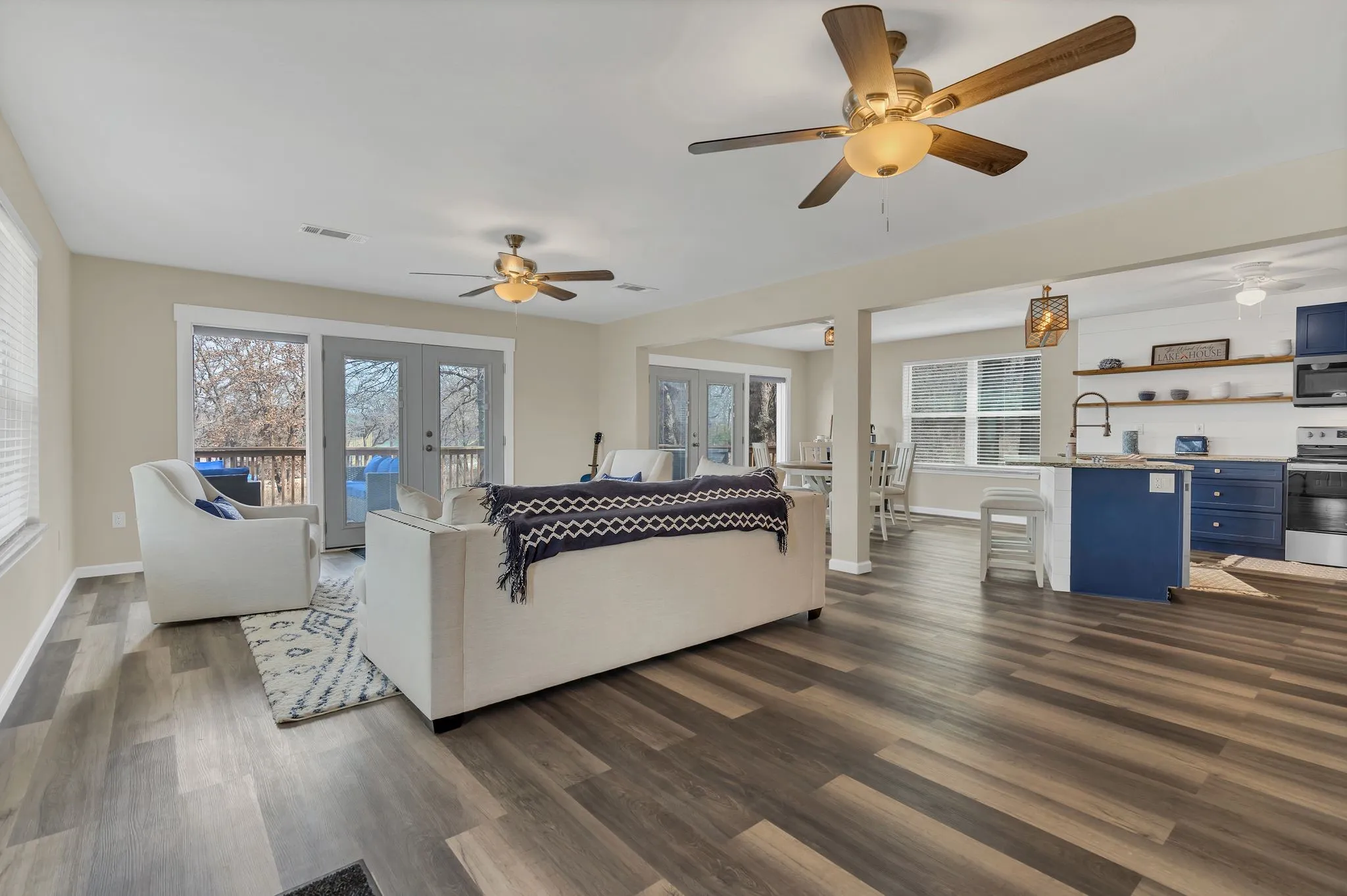 Wood-finish flooring throughout, two ceiling fans with integrated lighting, glass panel French doors, and an open-concept layout