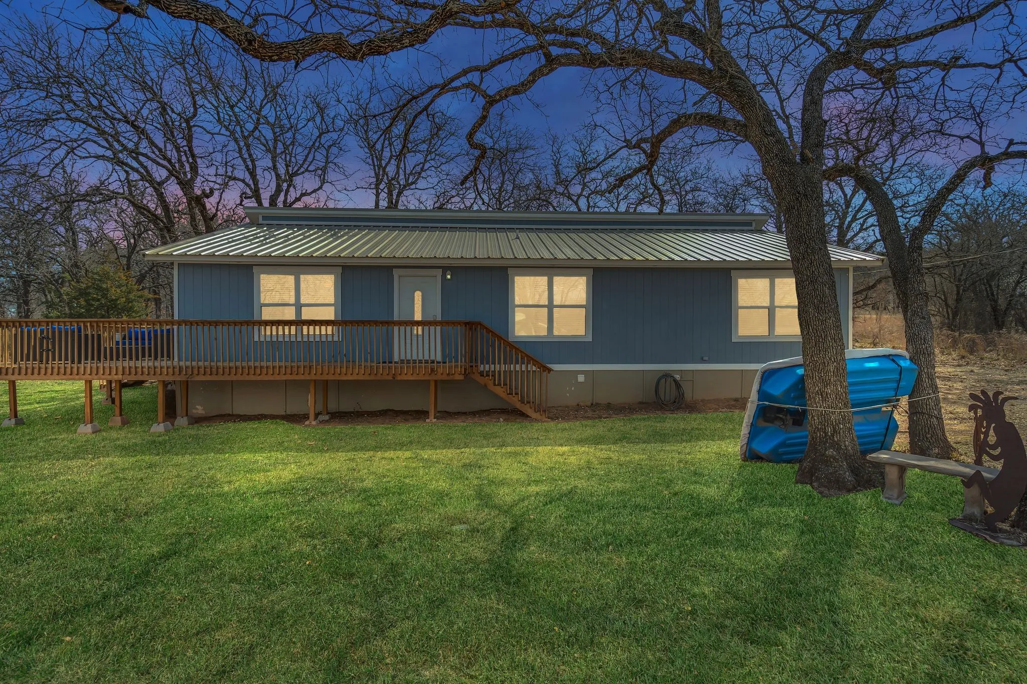 Blue exterior siding with white trim, metal roof, and an expansive wooden deck
