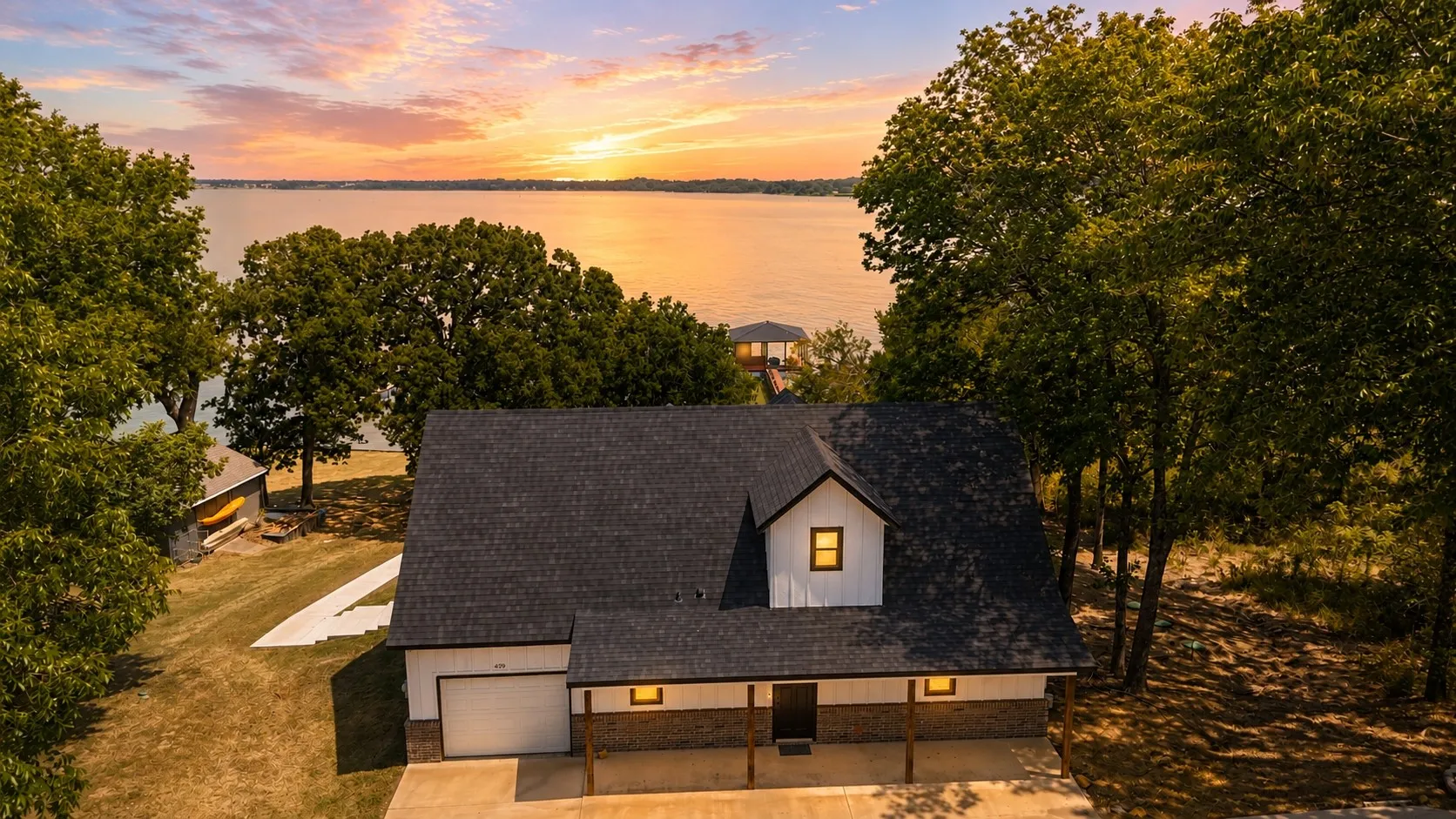Twilight aerial showcases this Richland Chambers Lake waterfront home surrounded by mature trees with beautiful open-water views in Corsicana, Texas.