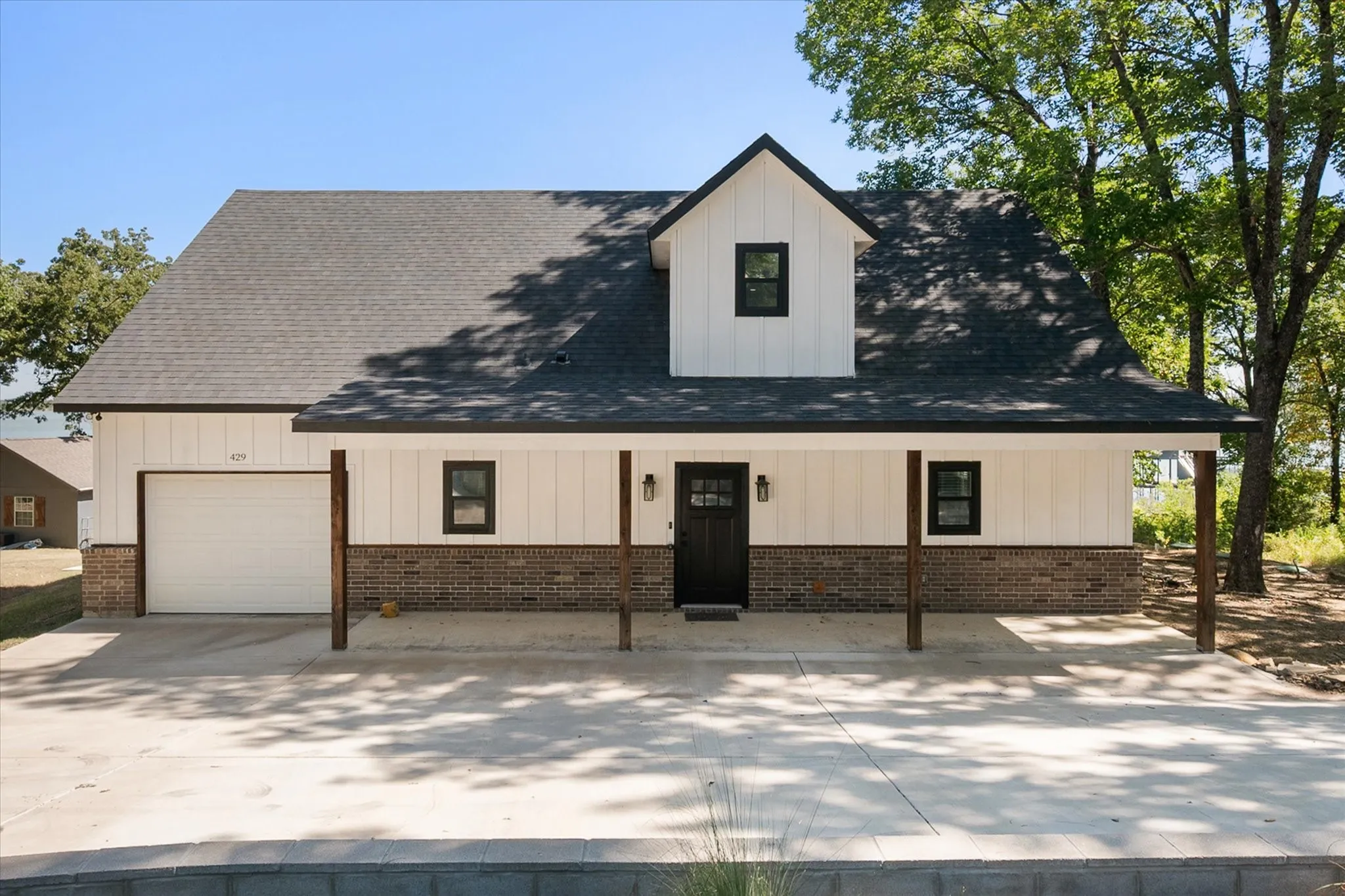 Front exterior showcases the modern farmhouse architecture, covered porch, attached one-car garage, and generous driveway parking.