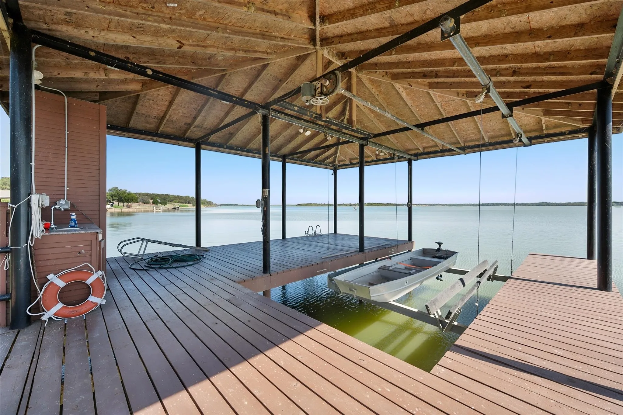 Spacious boathouse deck features a covered boat lift, waterfront seating space, and sweeping views across Richland Chambers Lake.