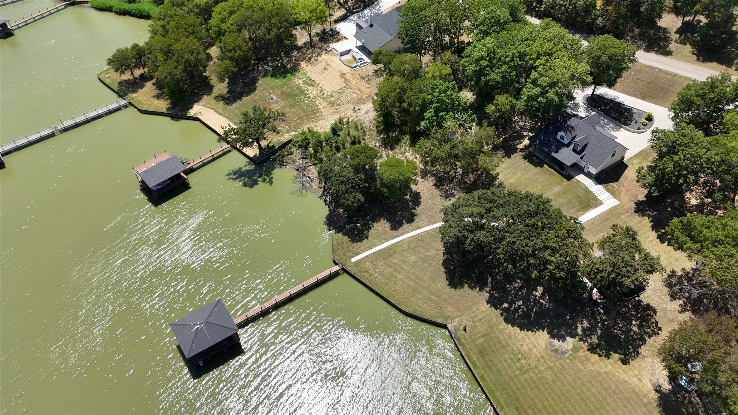 Aerial view highlights the property's main-body Richland Chambers Lake frontage, private boathouse, mature trees, and waterfront setting.