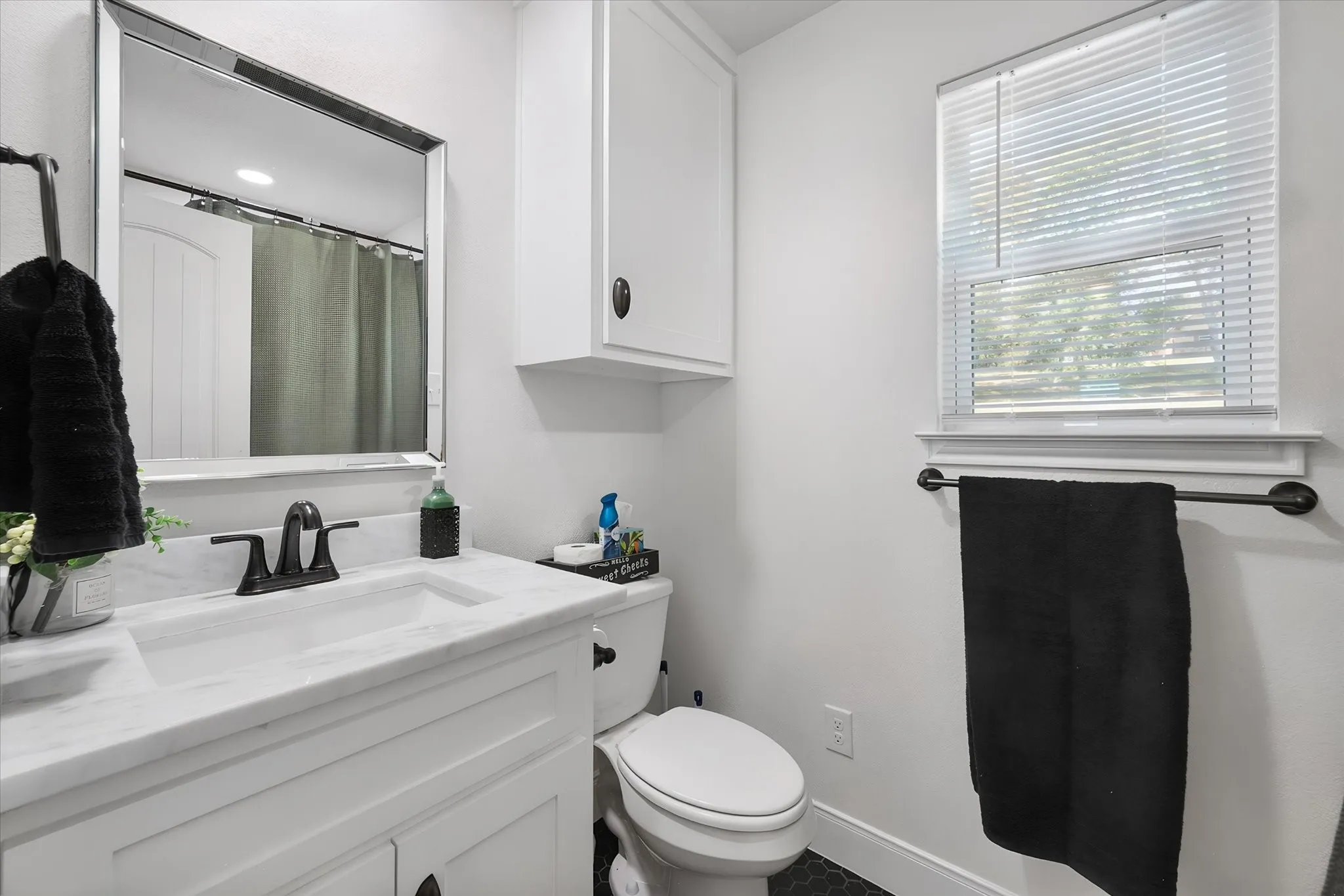 Bright guest bathroom offers a clean modern vanity, convenient storage, natural light, and contemporary finishes.