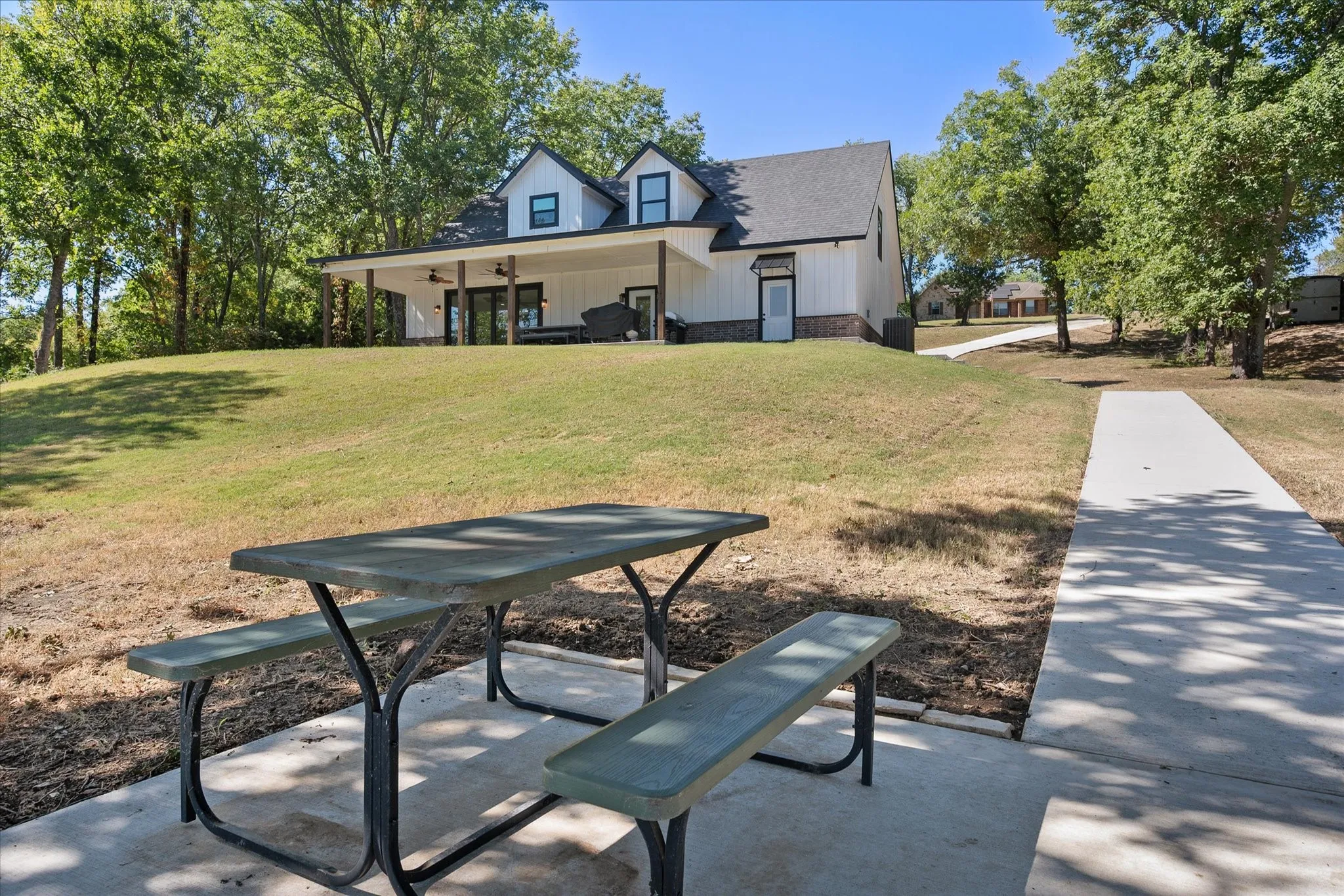 Concrete walkway leads across the spacious waterfront lawn toward the private boathouse, with a convenient picnic area for outdoor gatherings.