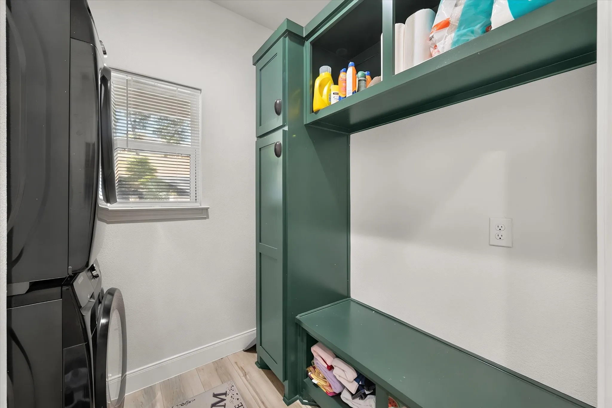 Dedicated laundry room maximizes functionality with a stacked washer and dryer plus extensive built-in storage and organization space.