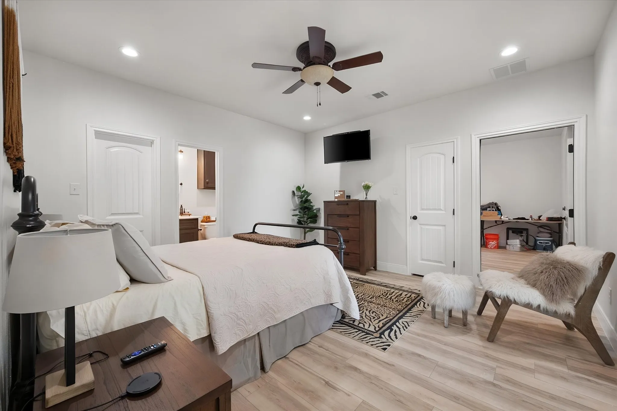 Spacious primary bedroom offers a relaxing main-level retreat with ceiling fan, hard-surface flooring, and convenient ensuite bath access.