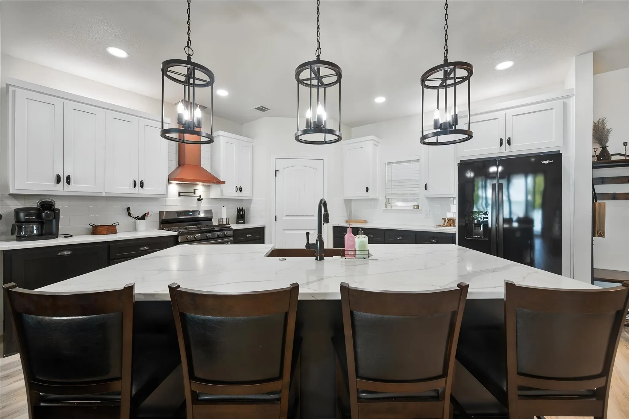 Expansive kitchen island provides generous seating beneath distinctive pendant lights in this beautifully appointed Corsicana waterfront home.