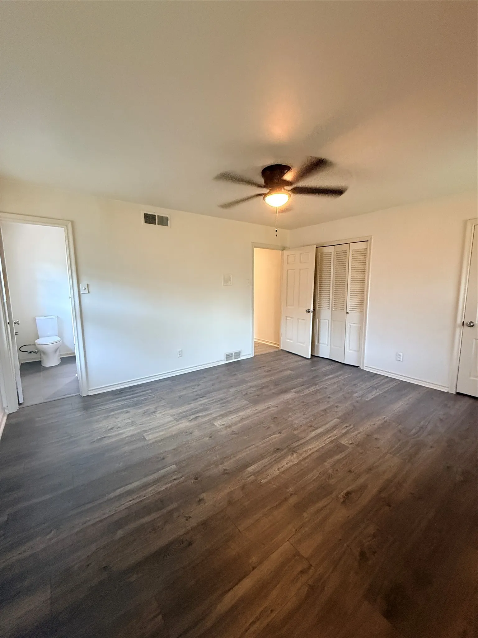 Wood-finish flooring, ceiling fan with integrated lighting, and white bi-fold closet doors