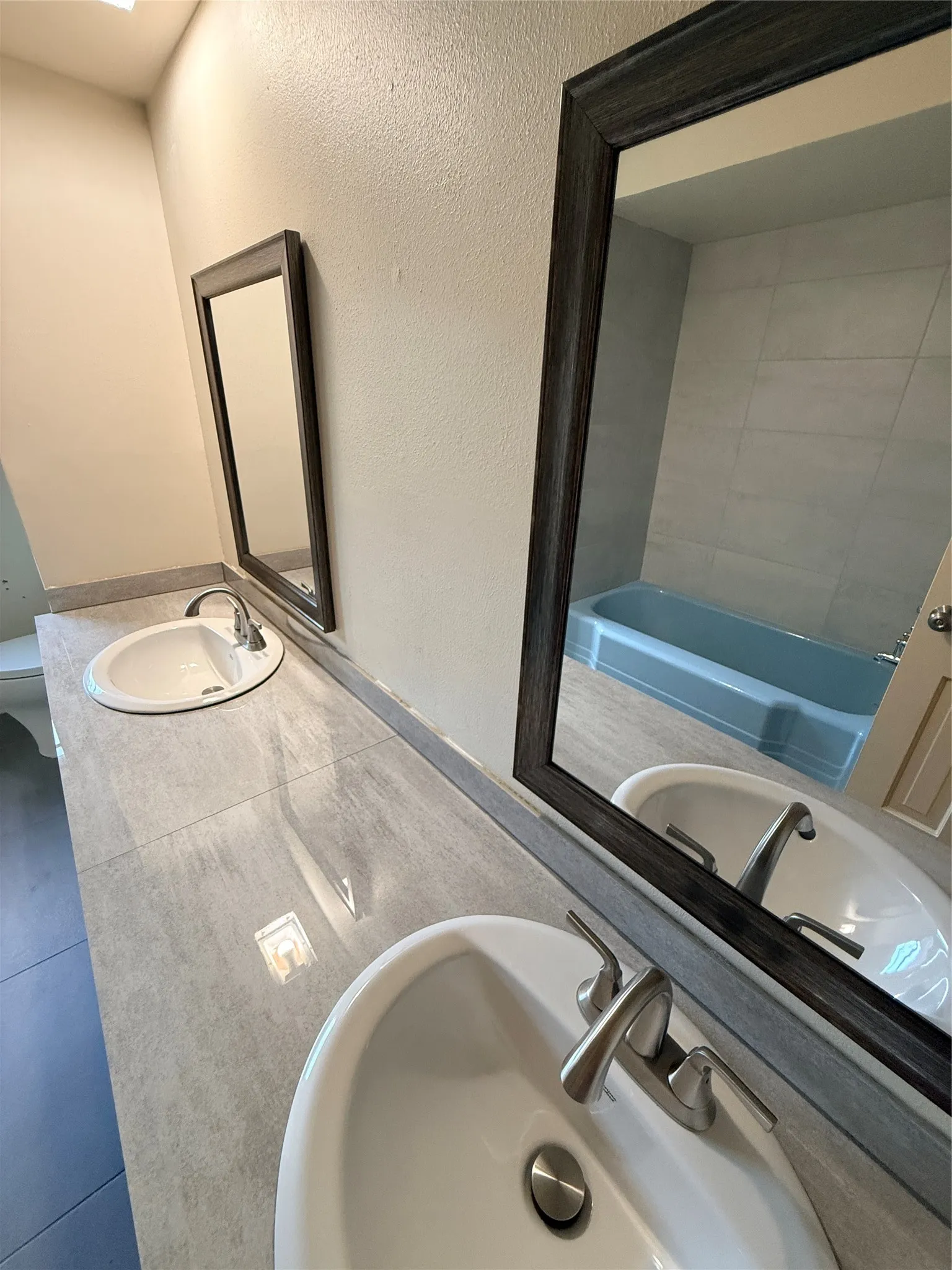 Dual undermount sinks, brushed nickel faucets, and a light gray countertop