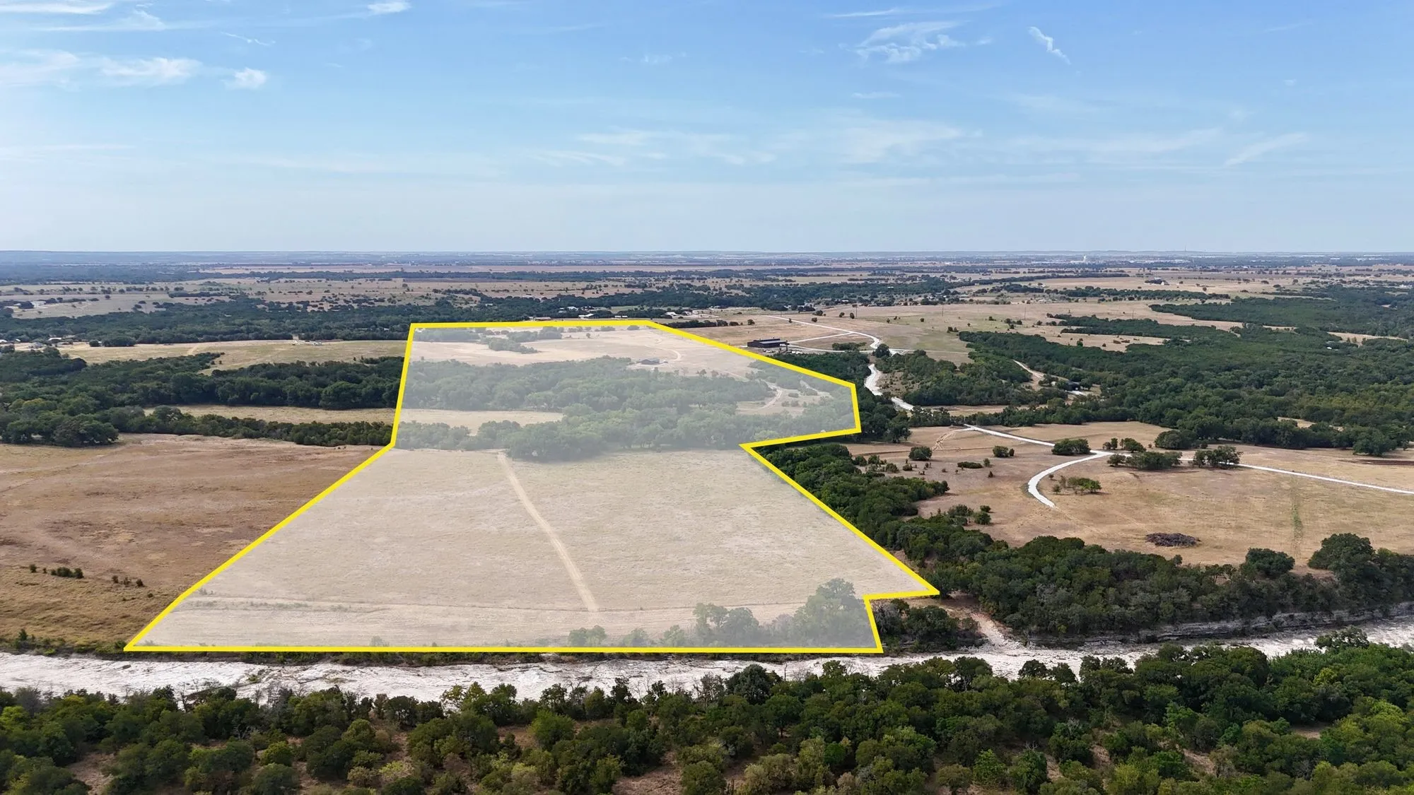 Expansive acreage featuring a mix of open fields and mature tree lines