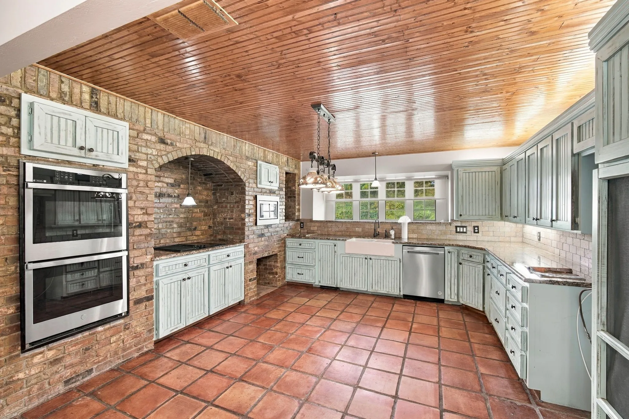 Notice the brick wall housing the double ovens, stove, microwave and cubbies for firewood.