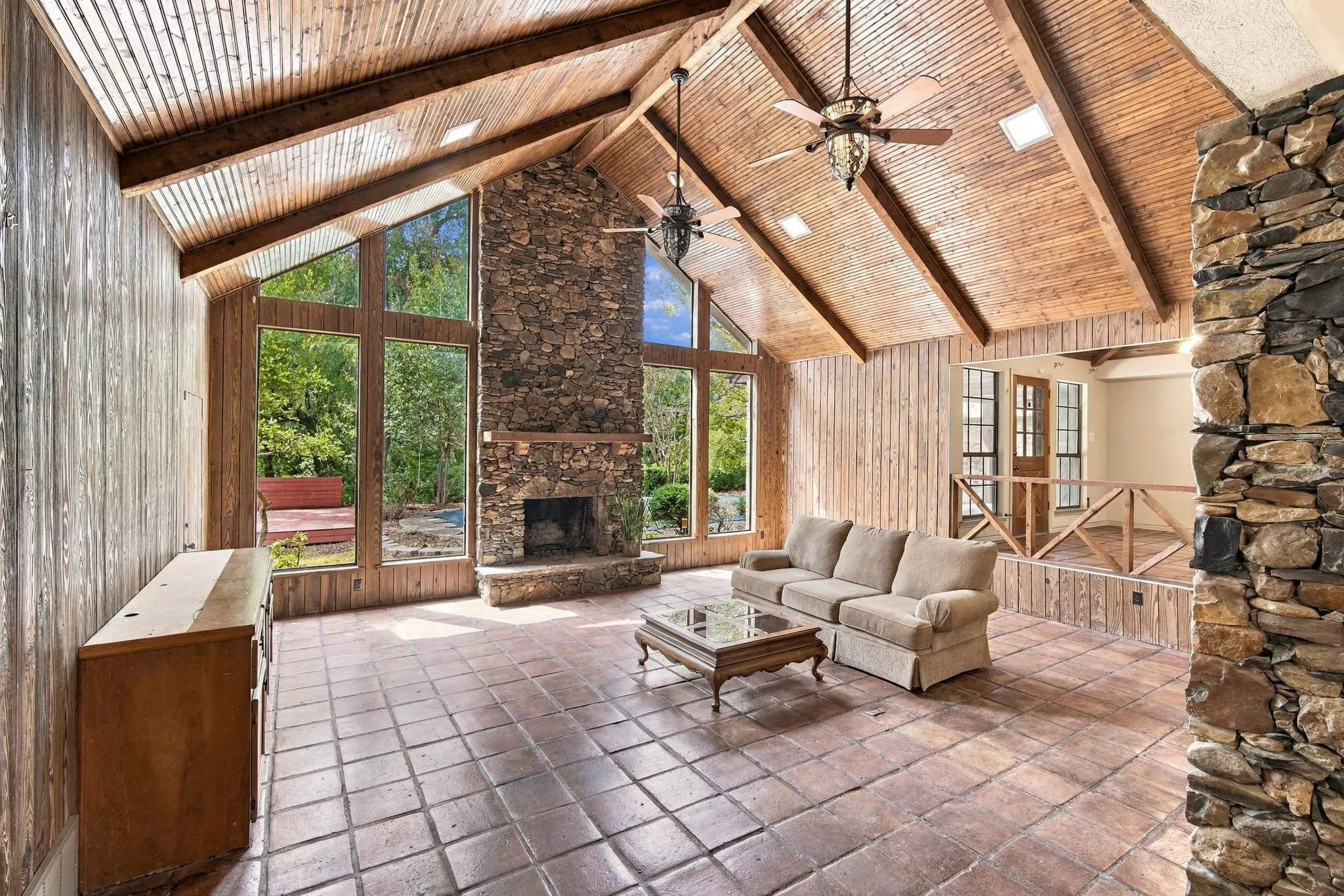 Enormous vaulted ceiling with Saltillo Tile, Rock Fireplace towering up to wooden clad ceiling with hardwood beams and a wall of windows to look out over the backyard.