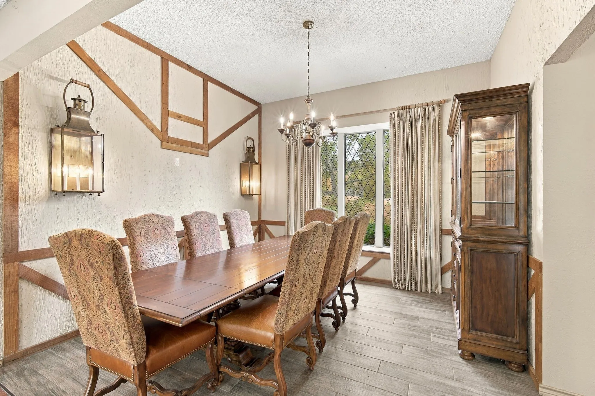 The wall trim and oversized sconces in this large dining space also add to the English Tudor style.