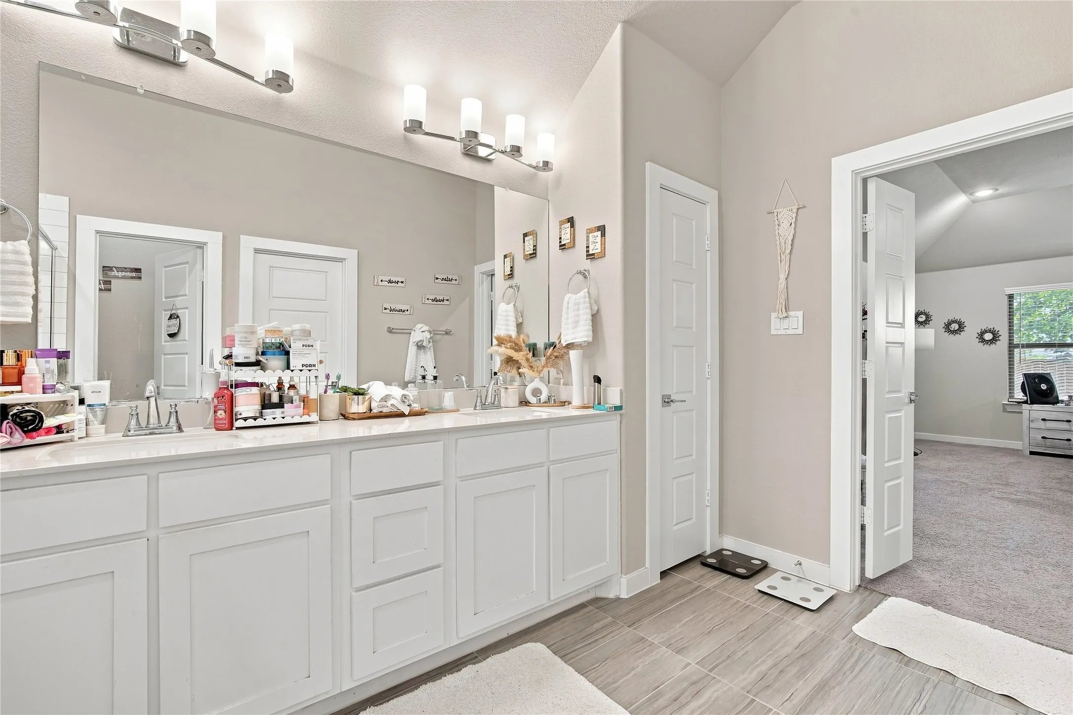 Double vanity with white cabinetry, dual undermount sinks, and a single large mirror