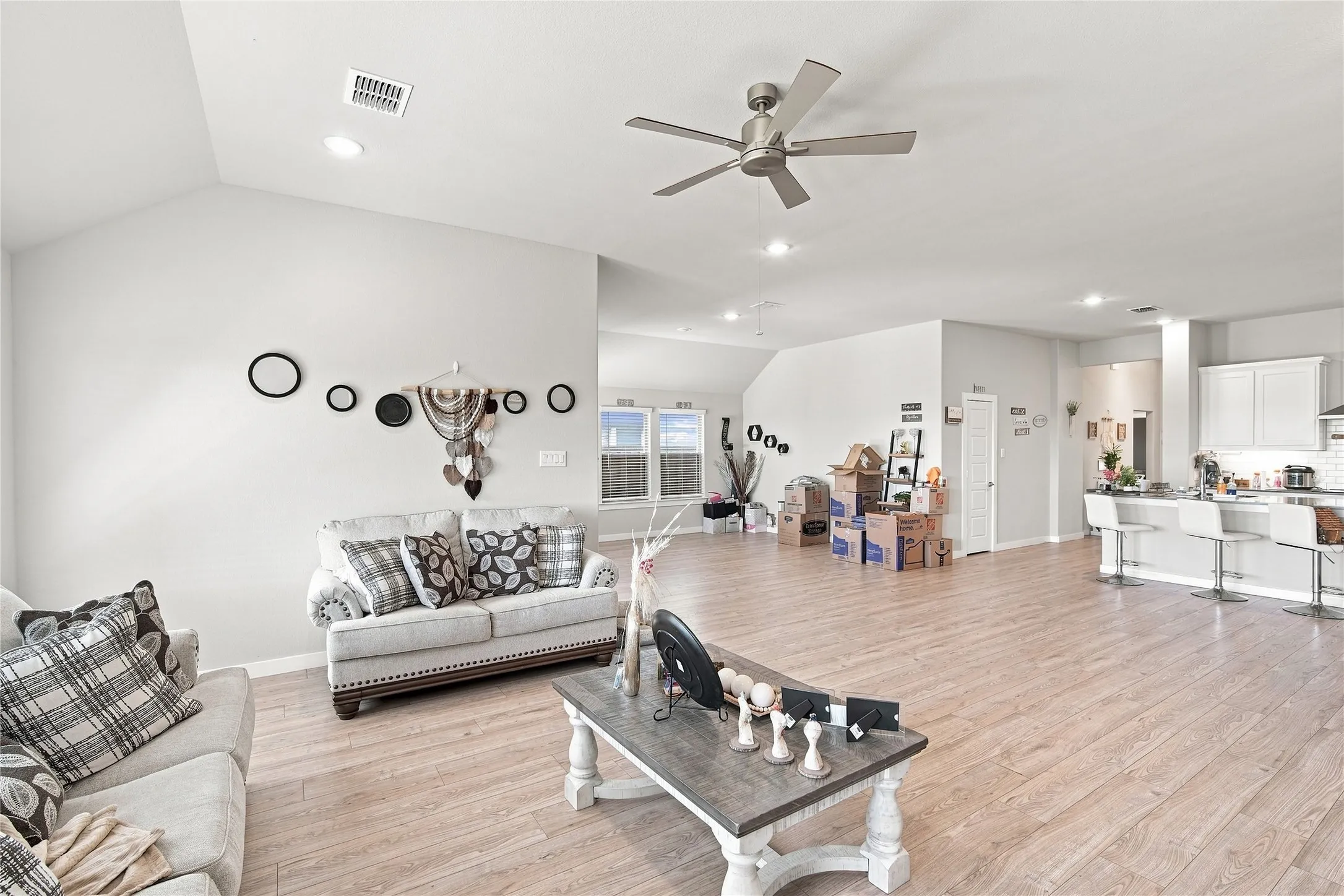 Vaulted ceiling with recessed lighting and ceiling fan, wood-finish flooring, and a kitchen island with seating