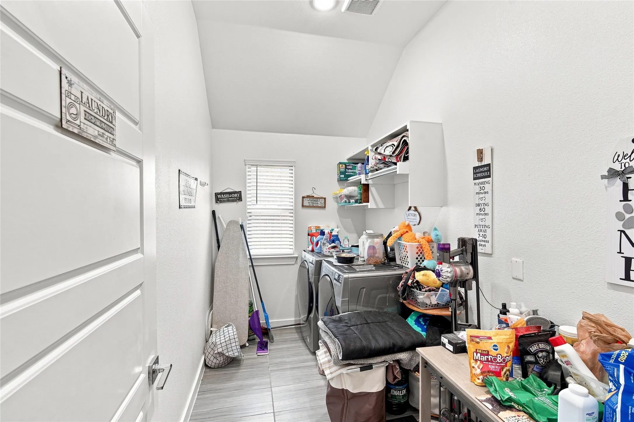 Laundry area featuring tile flooring, a window with blinds, and wall-mounted shelving