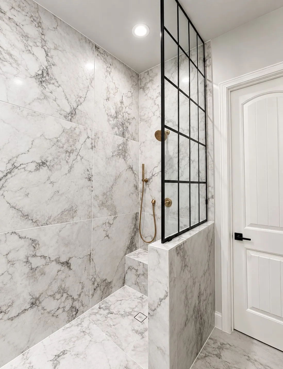 Walk-in shower featuring large format marble-look tile, a built-in shower bench, a black-framed glass partition, and brushed gold fixtures