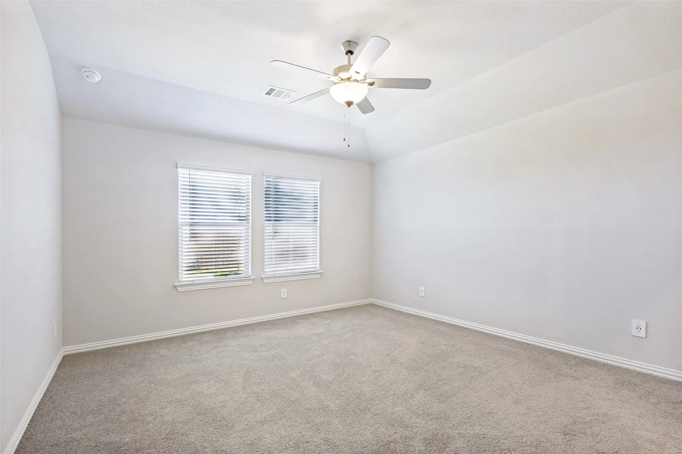 Recessed ceiling with a central ceiling fan, neutral wall paint, and gray carpet flooring